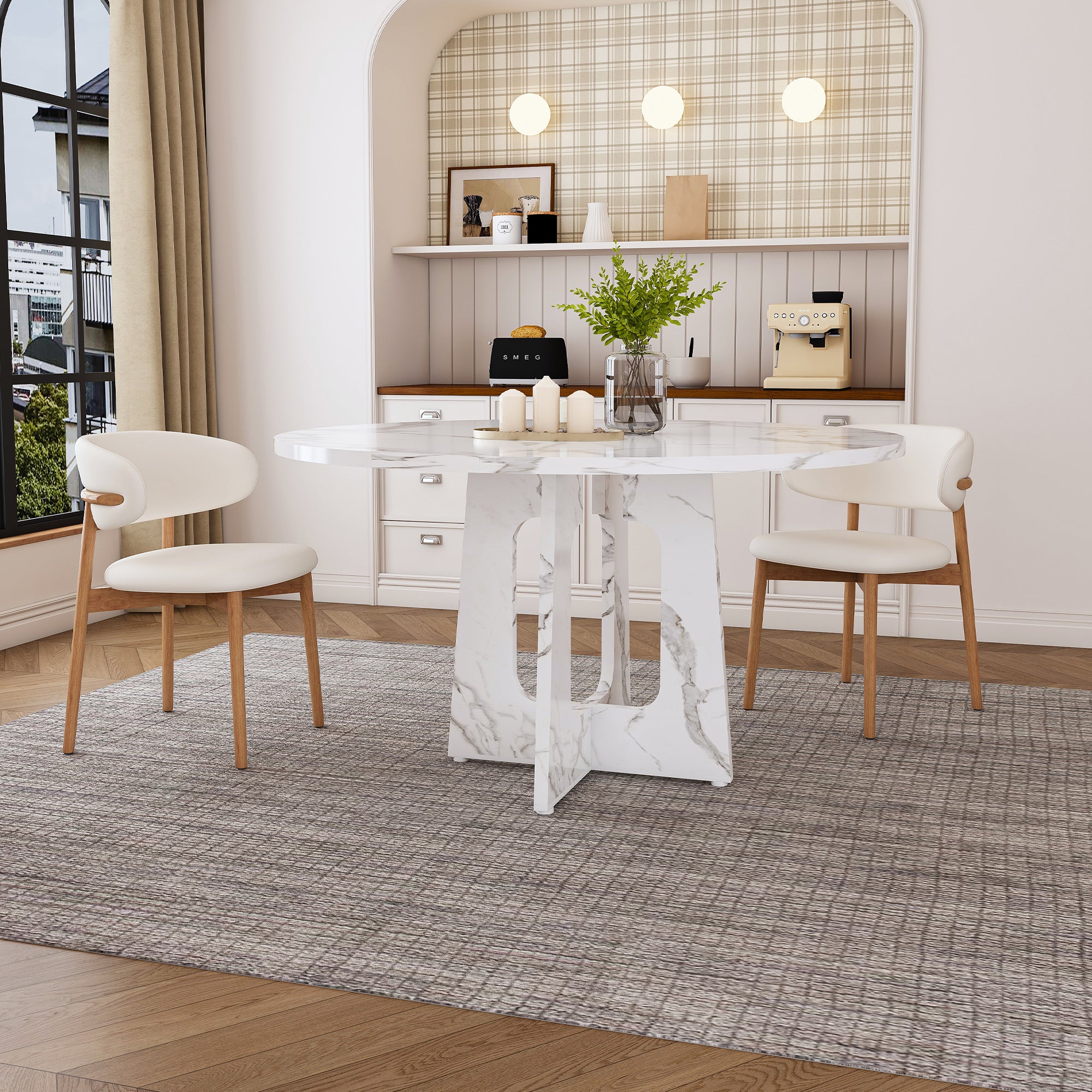 White faux marble round dining table with two cream chairs in a styled dining nook, angled view