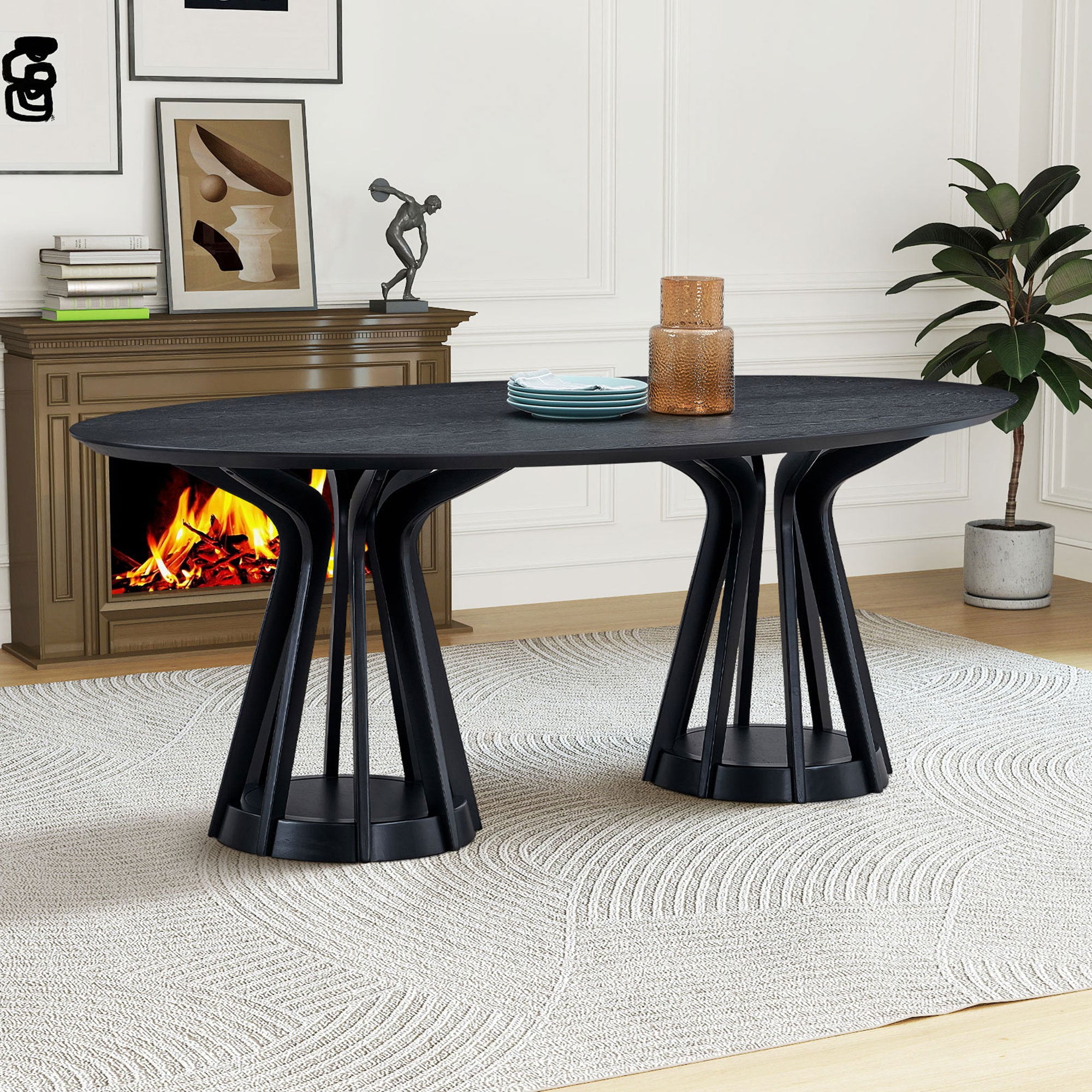 Black oval pedestal dining table styled in a room with fireplace, plates and vase on top