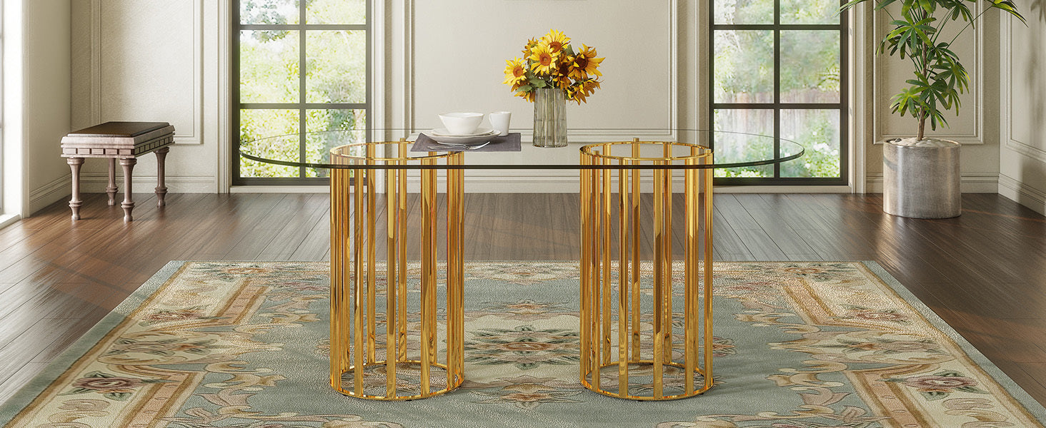 Angled room view of oval glass dining table with gold double-column base near a bench and potted plant