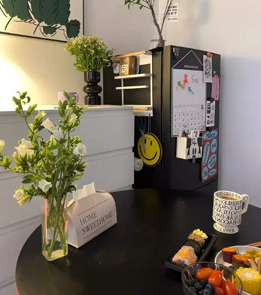 Black round dining table styled with flowers and sushi near a memo board, close view