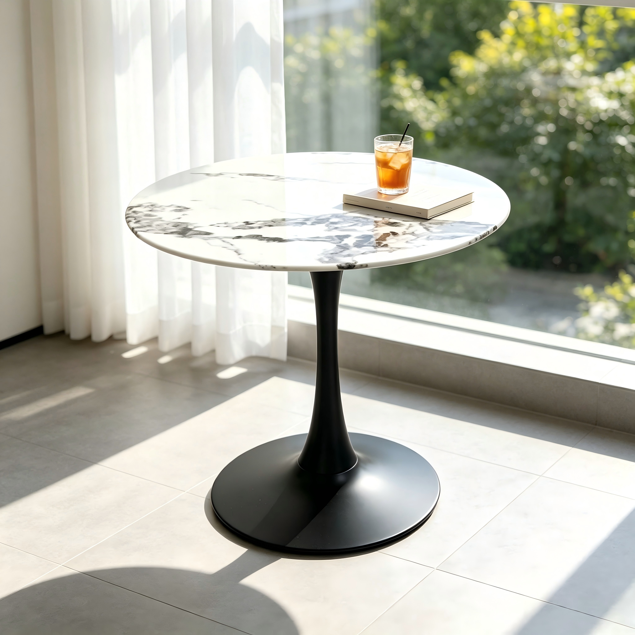 Three-quarter view of the white faux marble tulip table with black base in a sunlit room