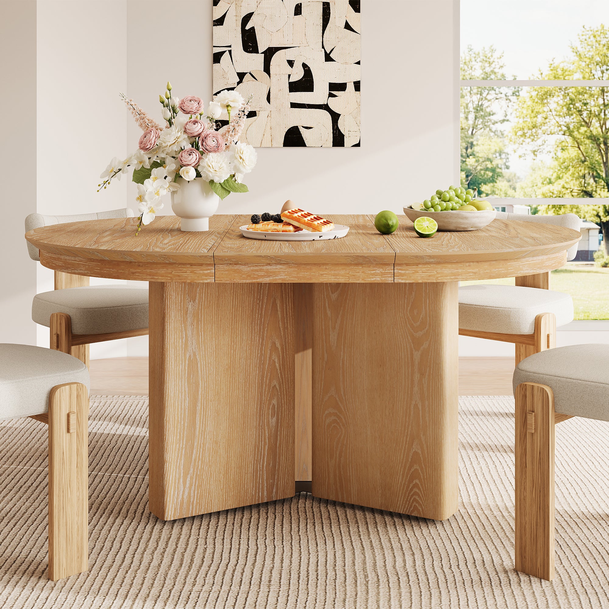 Round natural oak table styled with flowers, waffles and grapes among cream boucle chairs