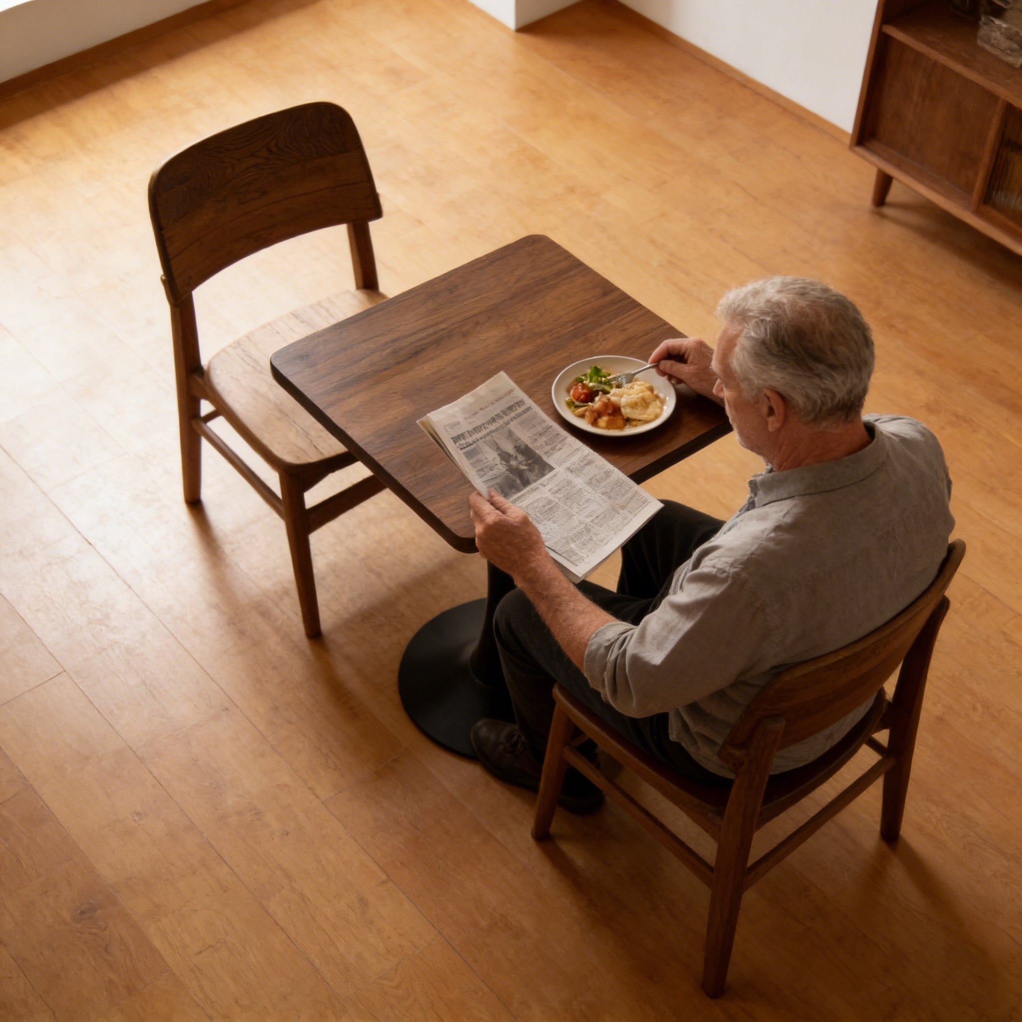 Three-quarter product photo of the walnut square tulip bistro table with a mug and books on a plain white background