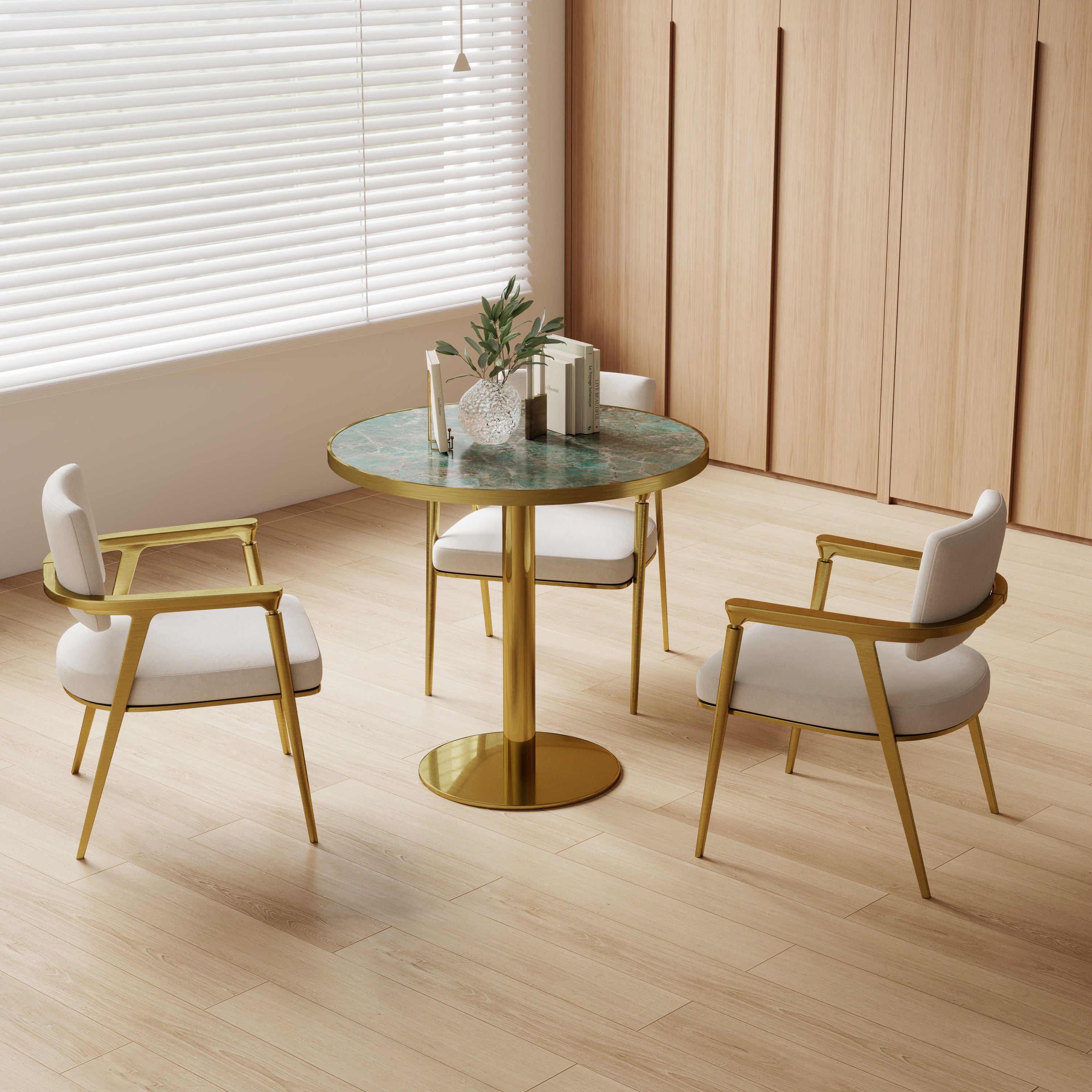 Green sintered stone round table styled in bright dining nook with two cream and gold chairs
