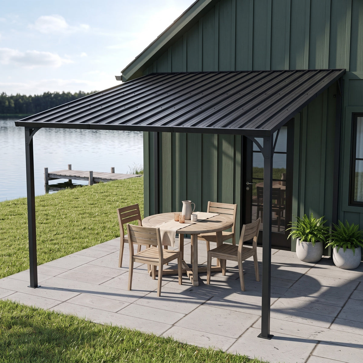 Black metal lean-to hardtop gazebo against a green house over a round wood dining set on a lakeside patio