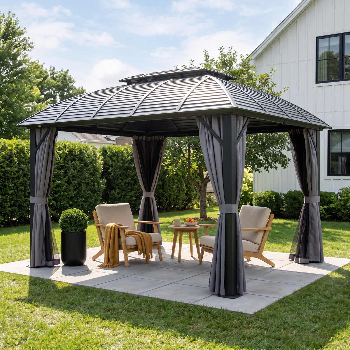 Black aluminum 10x12 double roof hardtop gazebo with gray curtains tied back over two lounge chairs on a paver patio