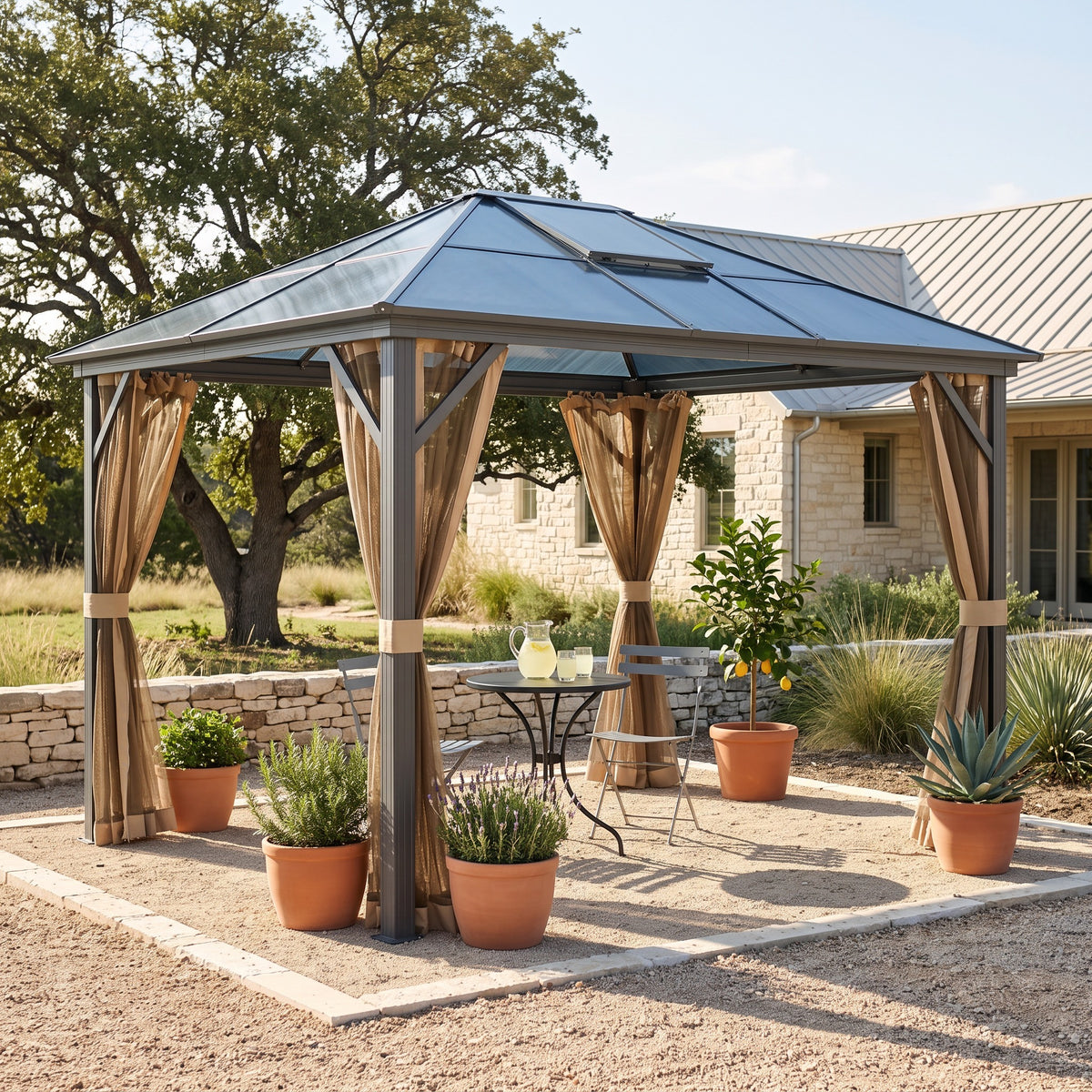 Gray aluminum hardtop gazebo with tan mesh netting over a bistro table on a gravel patio by a stone house