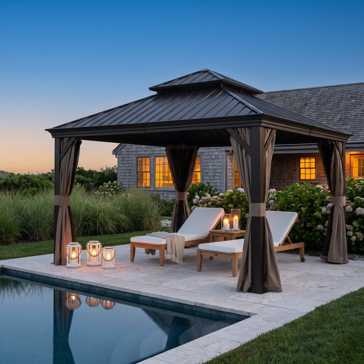 Brown aluminum 12x12 double roof hardtop gazebo with tied back curtains over two lounge chairs by a pool at dusk