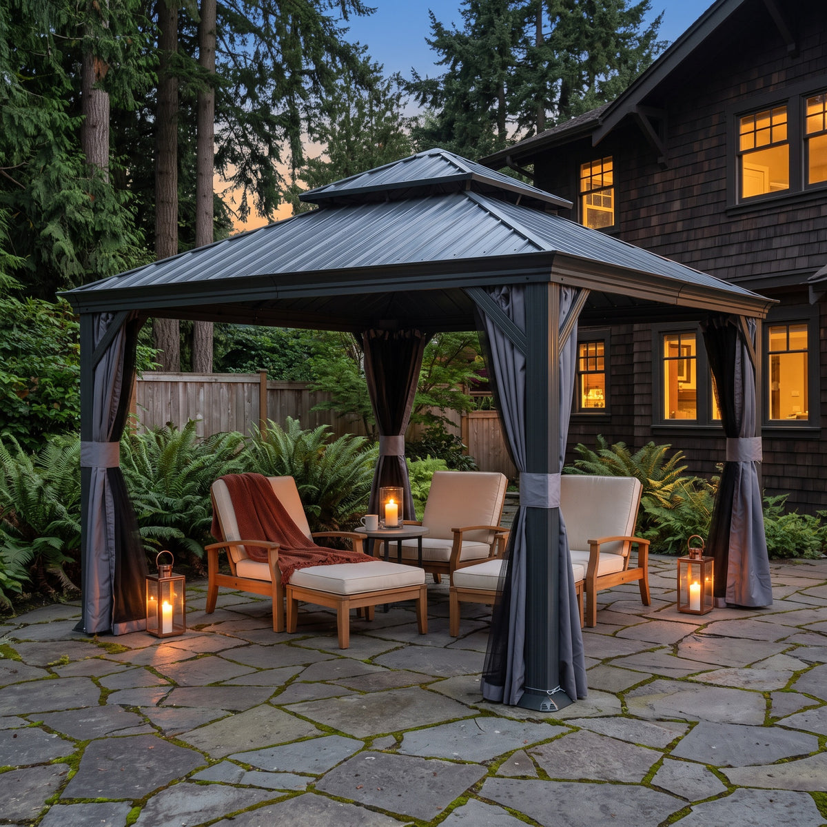 Gray aluminum 12x12 double roof hardtop gazebo with tied back curtains over teak lounge chairs on a stone patio at dusk