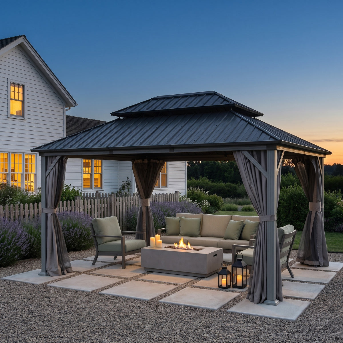 Gray aluminum 12x14 double roof hardtop gazebo with tied back curtains over a fire table and sofa on a gravel patio at dusk