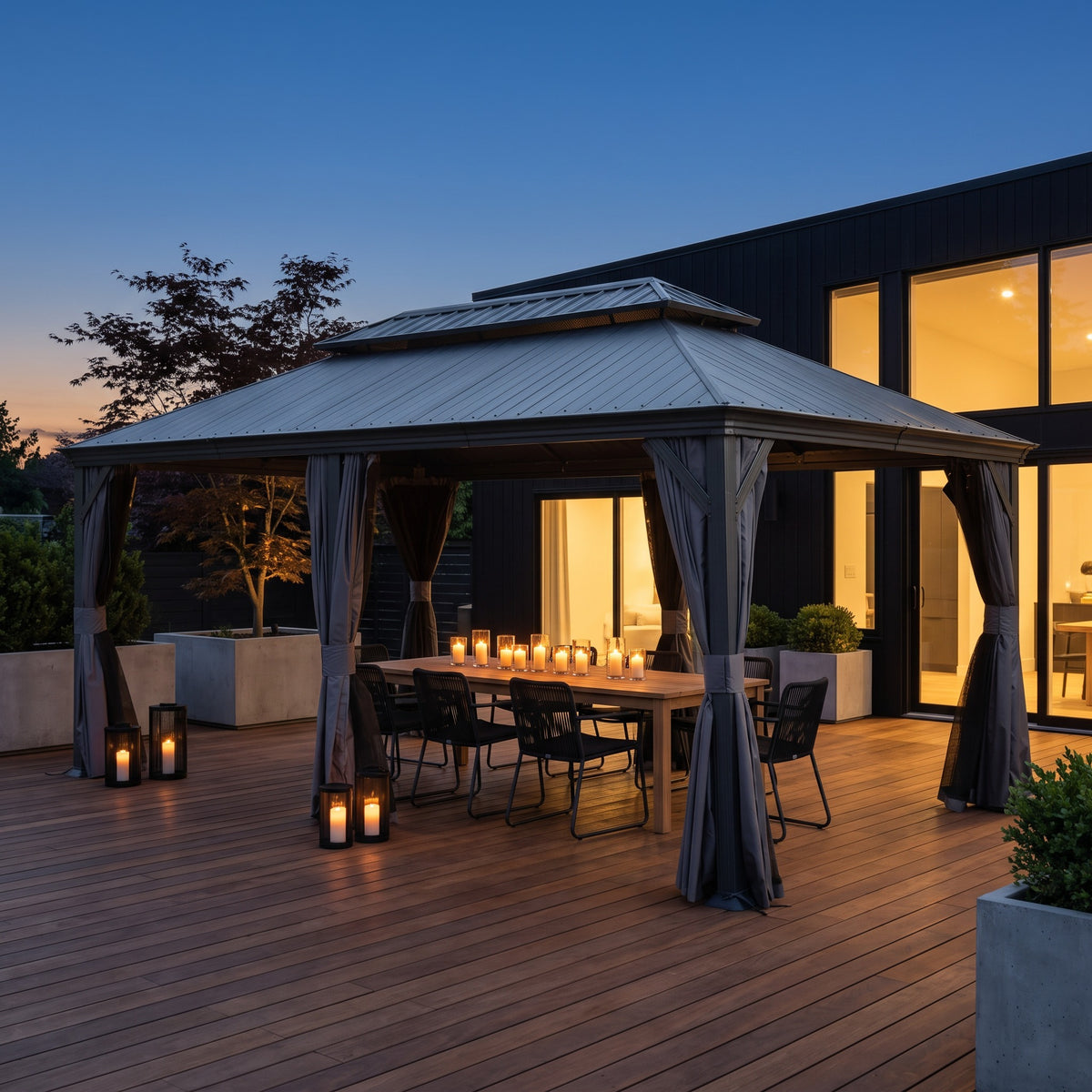 Dark gray 12x20 hardtop gazebo with curtains tied back over a candlelit dining table on a wood deck at dusk