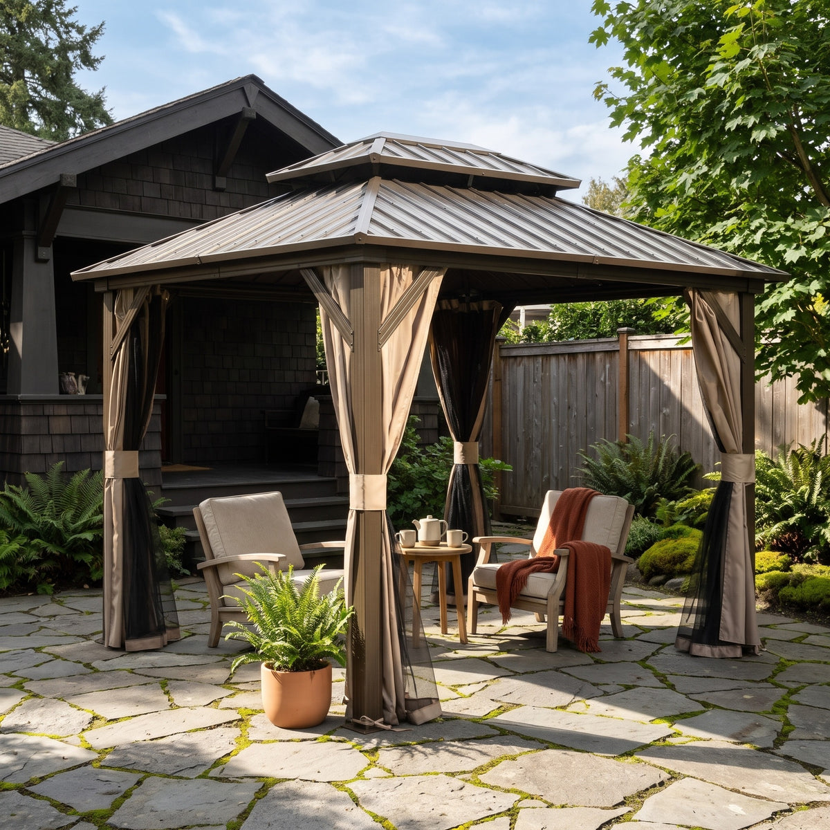 Brown aluminum 8x10 double roof hardtop gazebo with tied back curtains over two lounge chairs on a stone patio