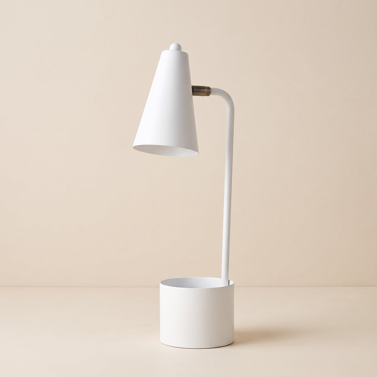 White metal desk lamp with cone shade, brass finish joint and cup base on a warm ivory backdrop