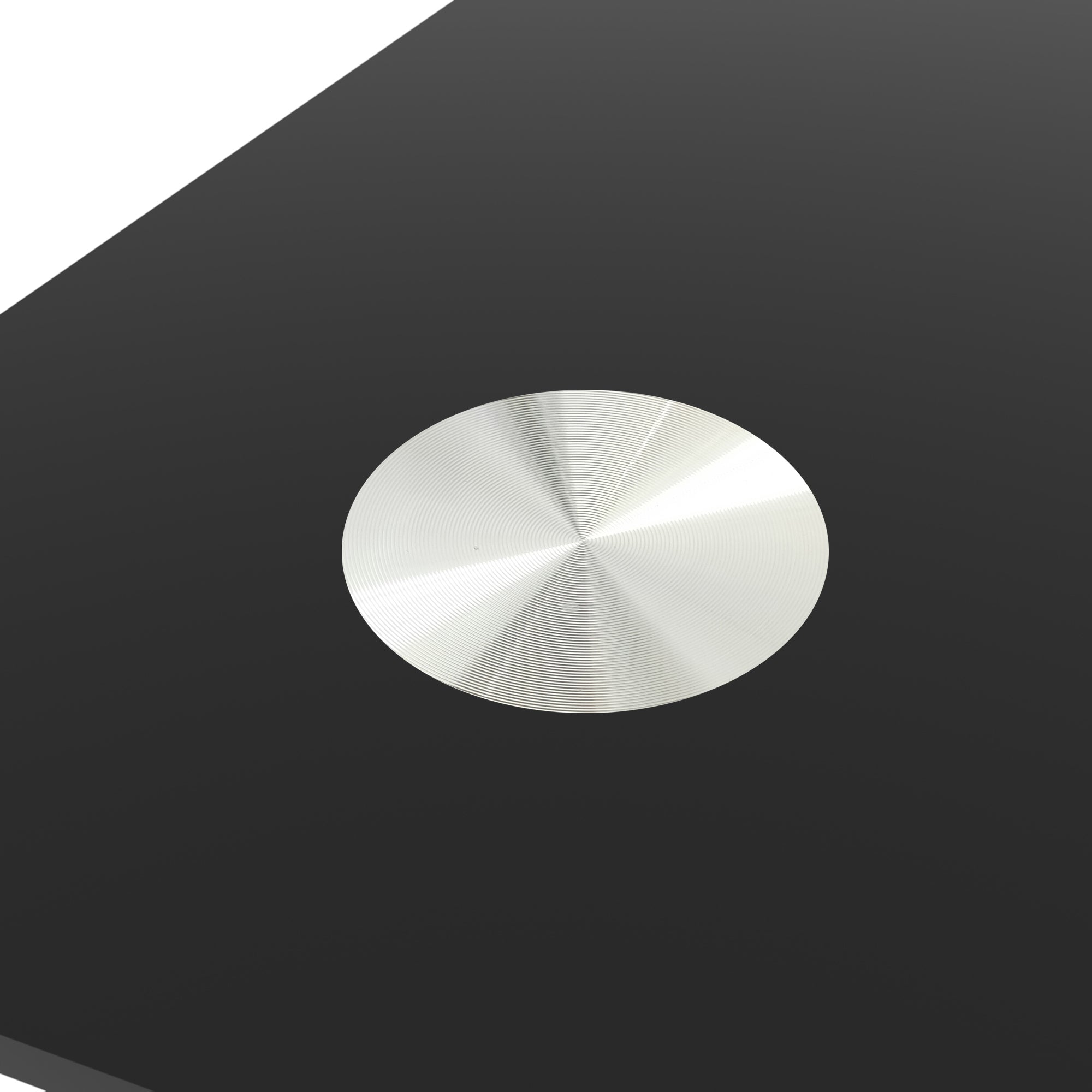 Overhead close-up of the brushed aluminum disk connector on the black glass top