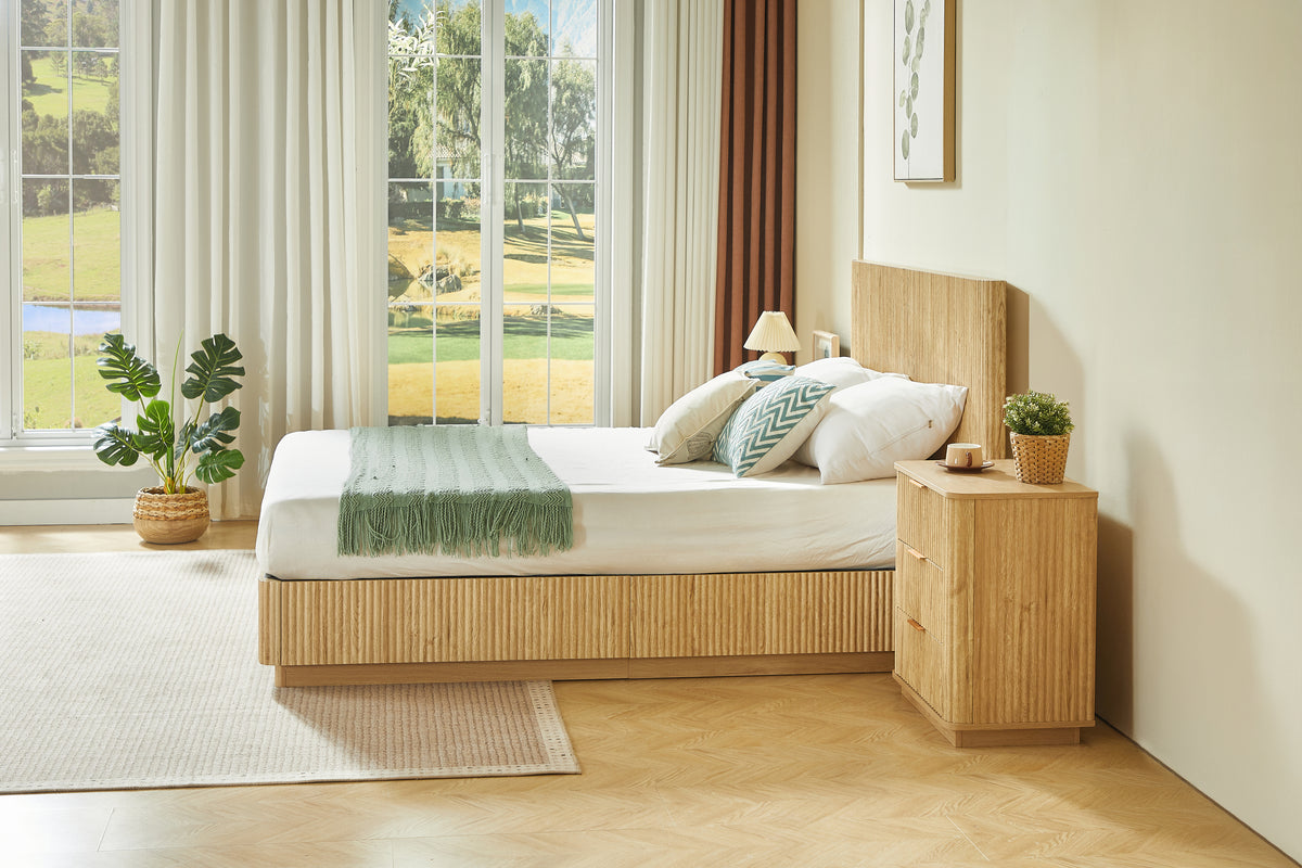 Side view of light oak fluted queen bed by a sunlit window with green throw and nightstand