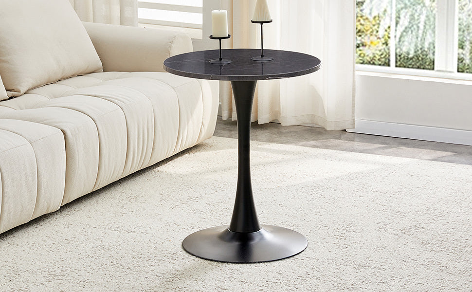 Black marble-look bistro table with candle holders close beside a cream tufted sofa, three-quarter view