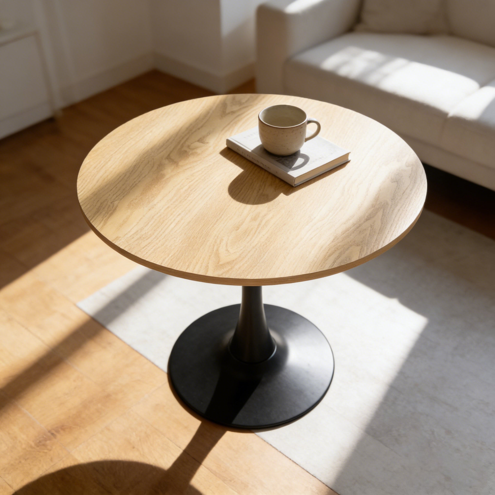 Overhead view of the natural round pedestal dining table with a cup resting on a book