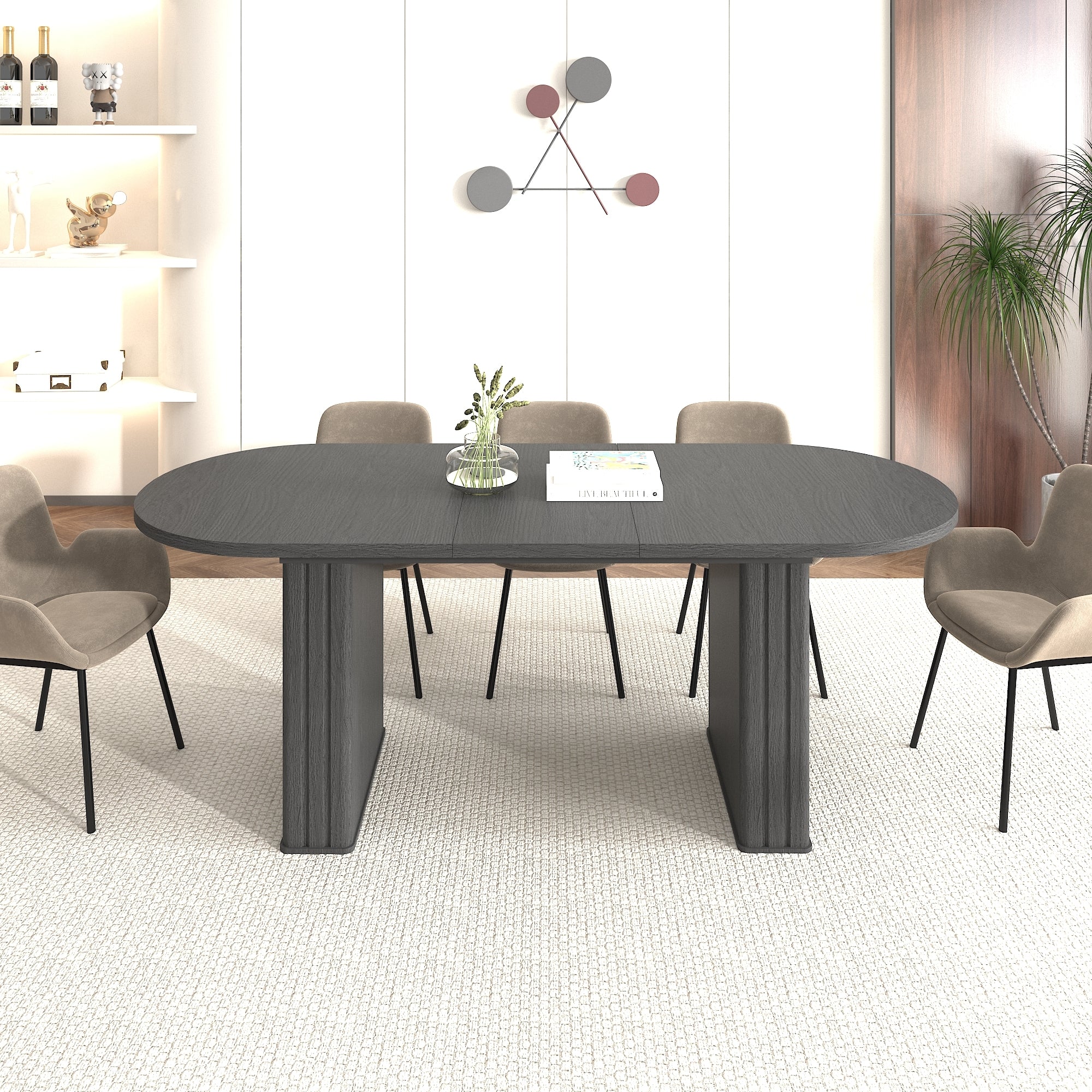 Three-quarter view of the black oval extendable dining table with tan dining chairs and books on top