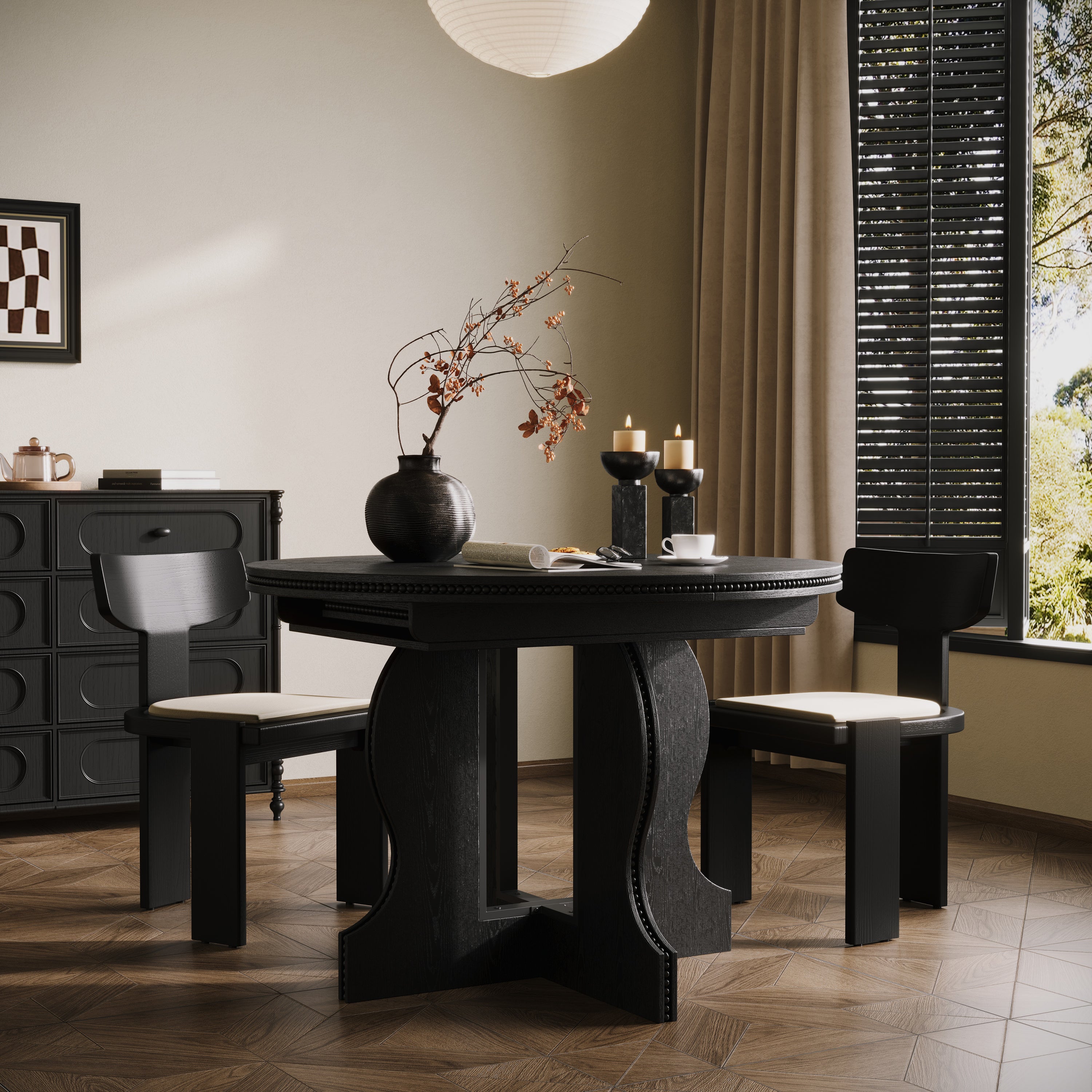 Black round pedestal dining table with two chairs near a shuttered window in a styled dining room