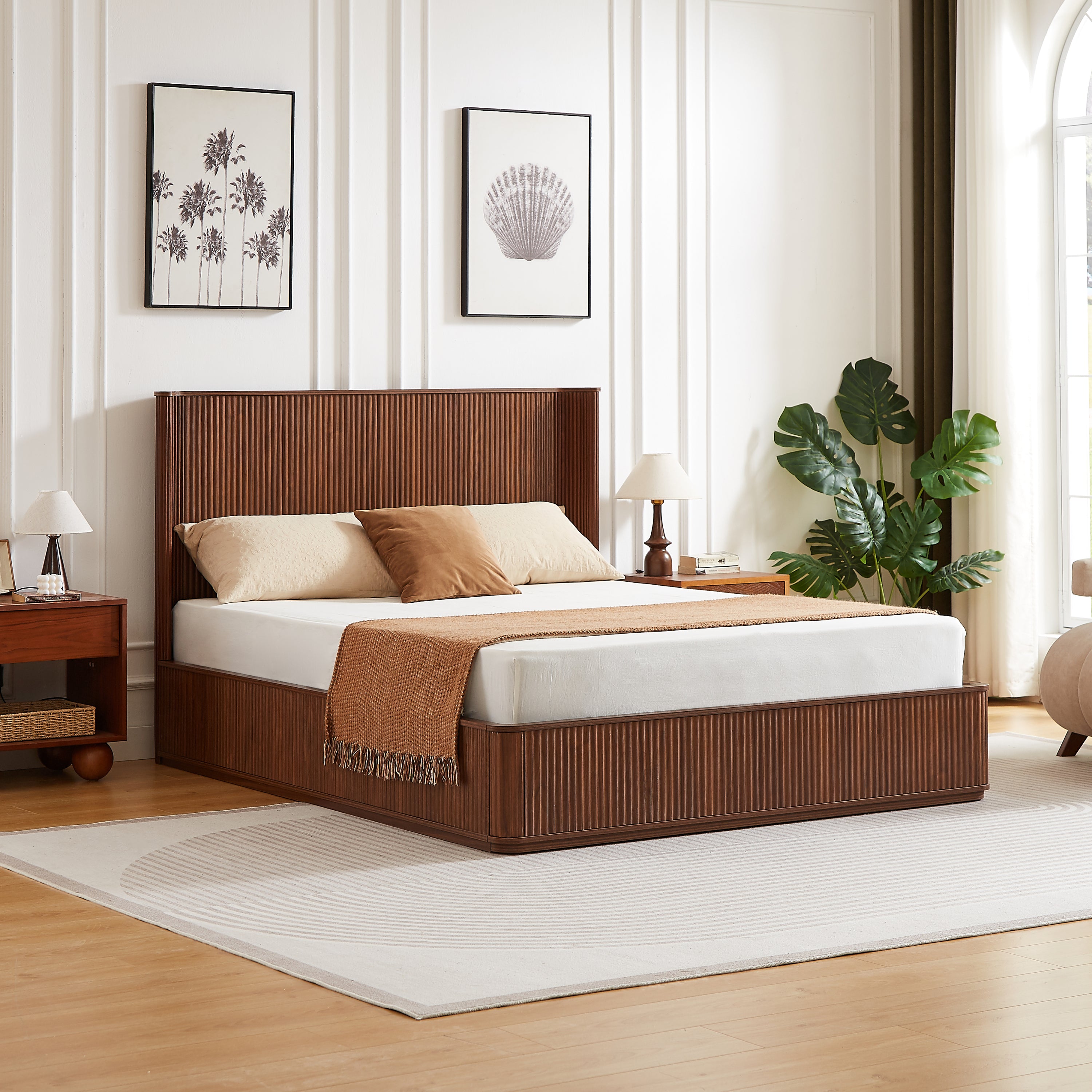 Angled view of the walnut tall queen bed frame in a bright room with a monstera plant, vertical fluted headboard and footboard #Color_Walnut