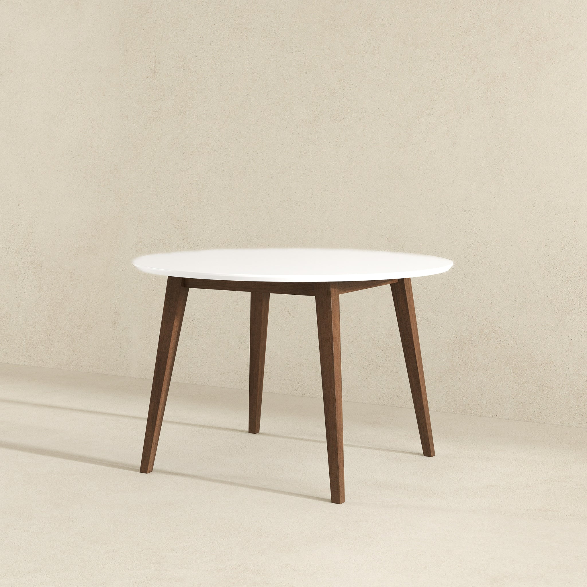 White round dining table with walnut legs, three-quarter view on beige background