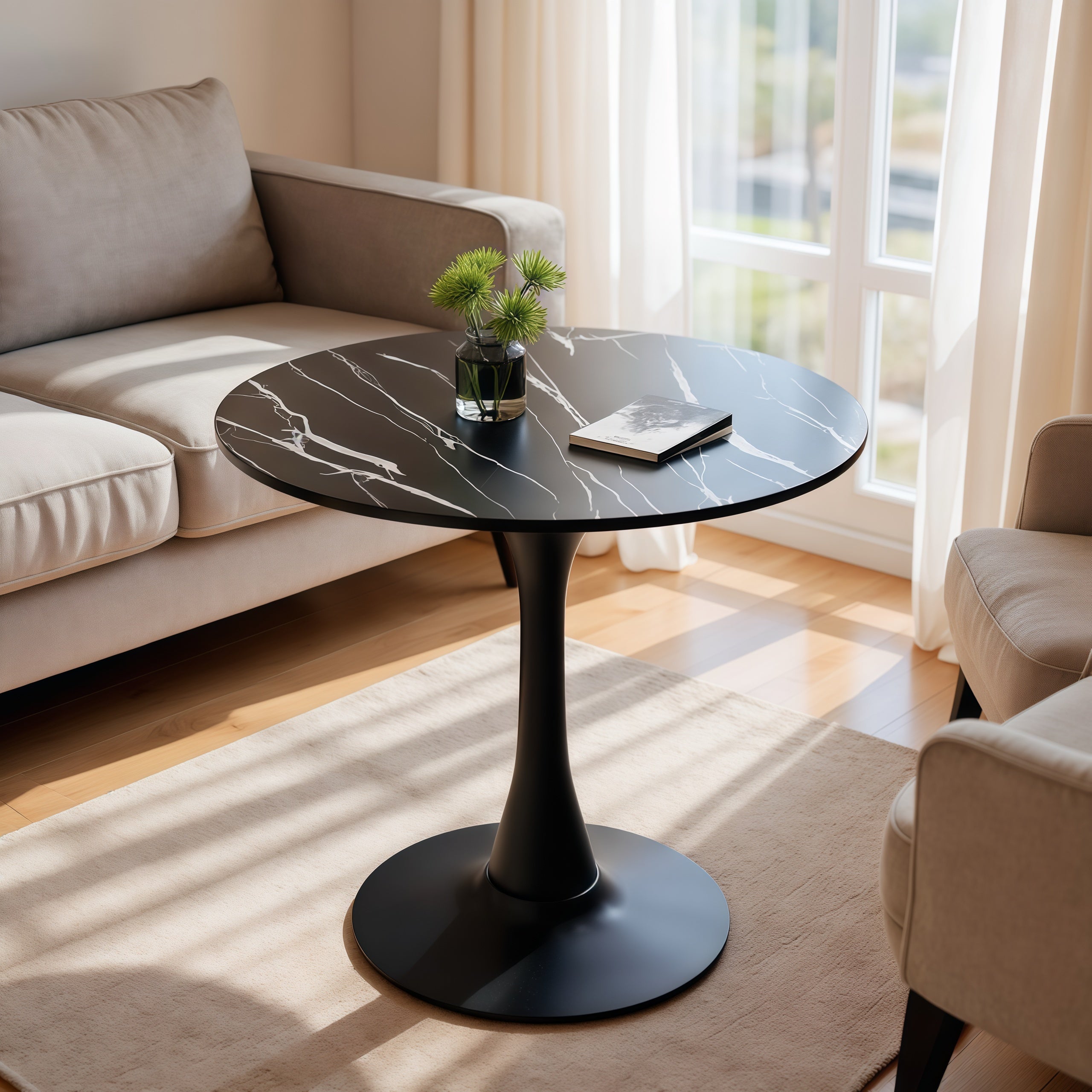 Black marble round table styled with flowers and a book between two beige sofas