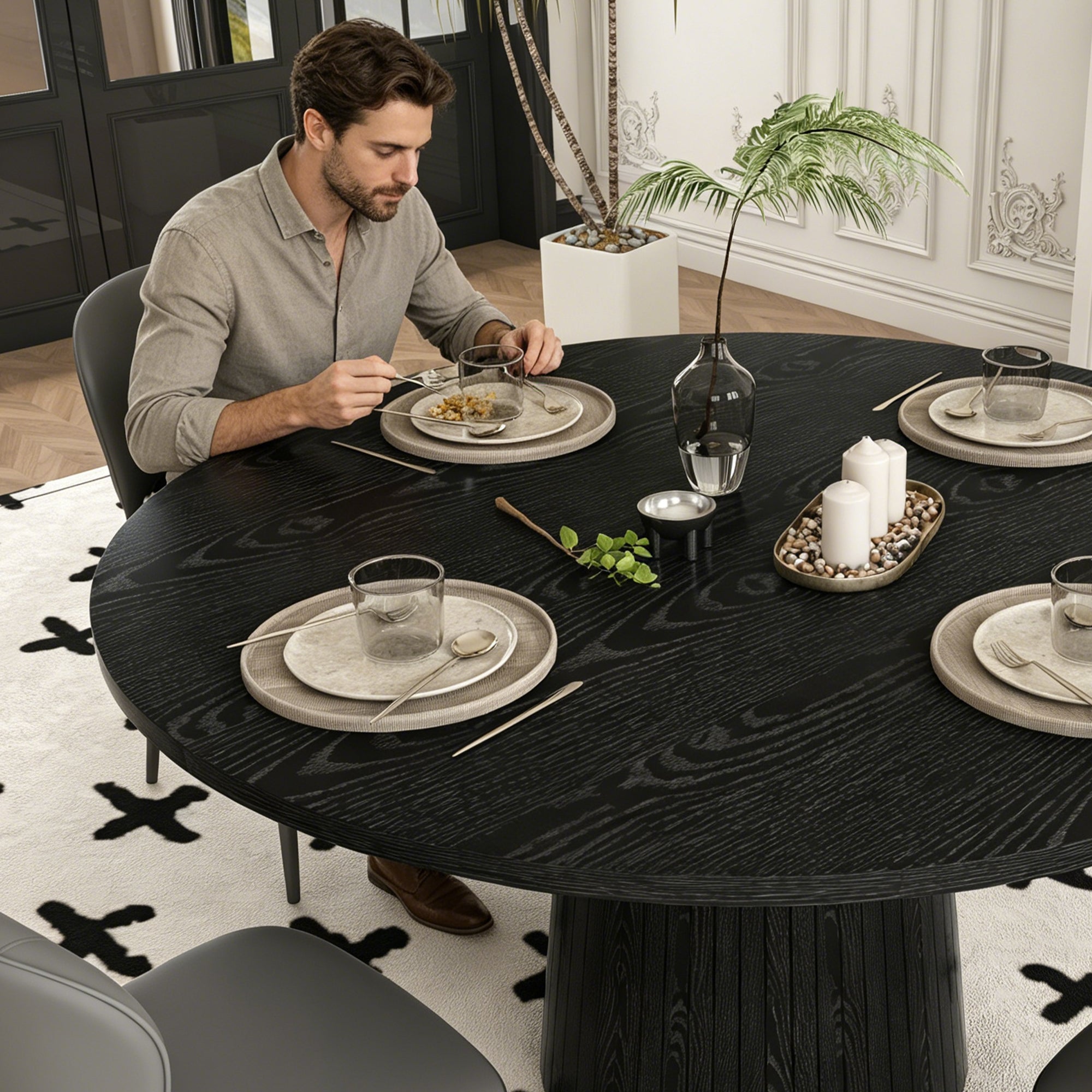 Man seated eating at the black round dining table with gray chairs, high angle view