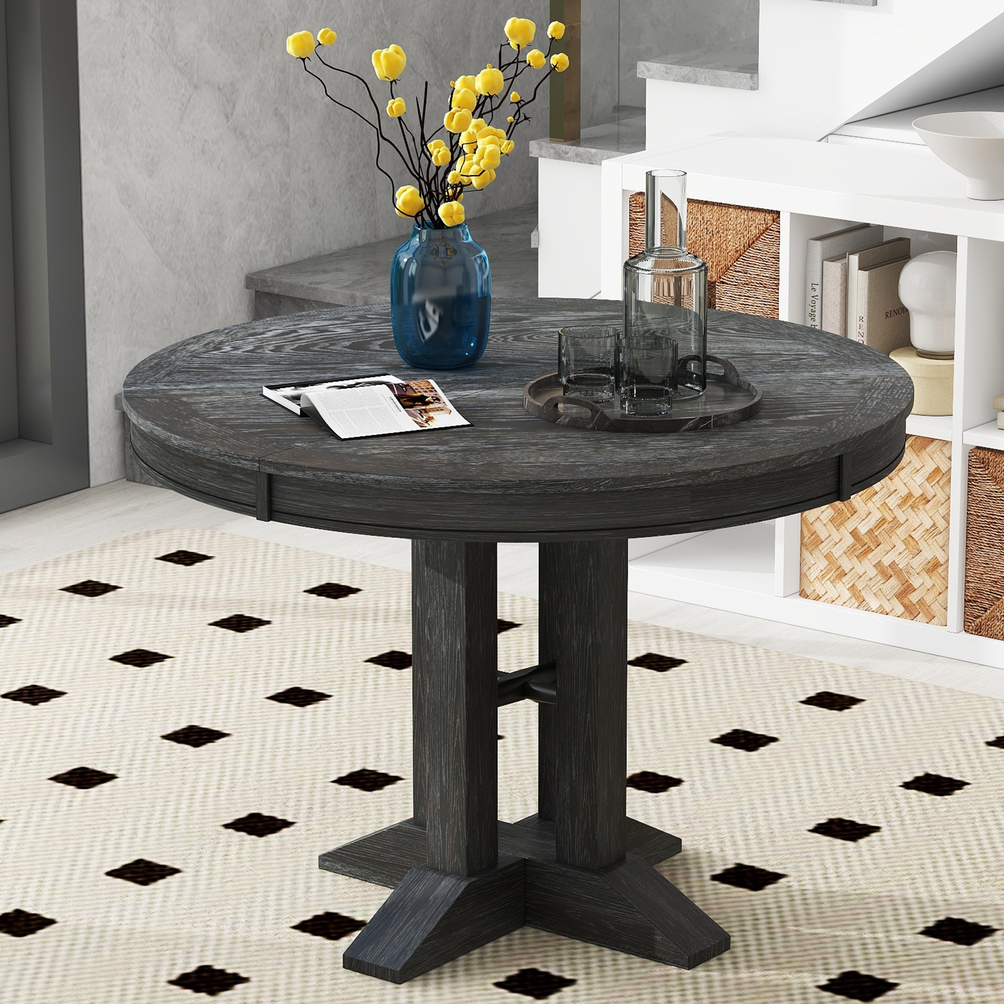 Black round dining table in a styled room near a staircase