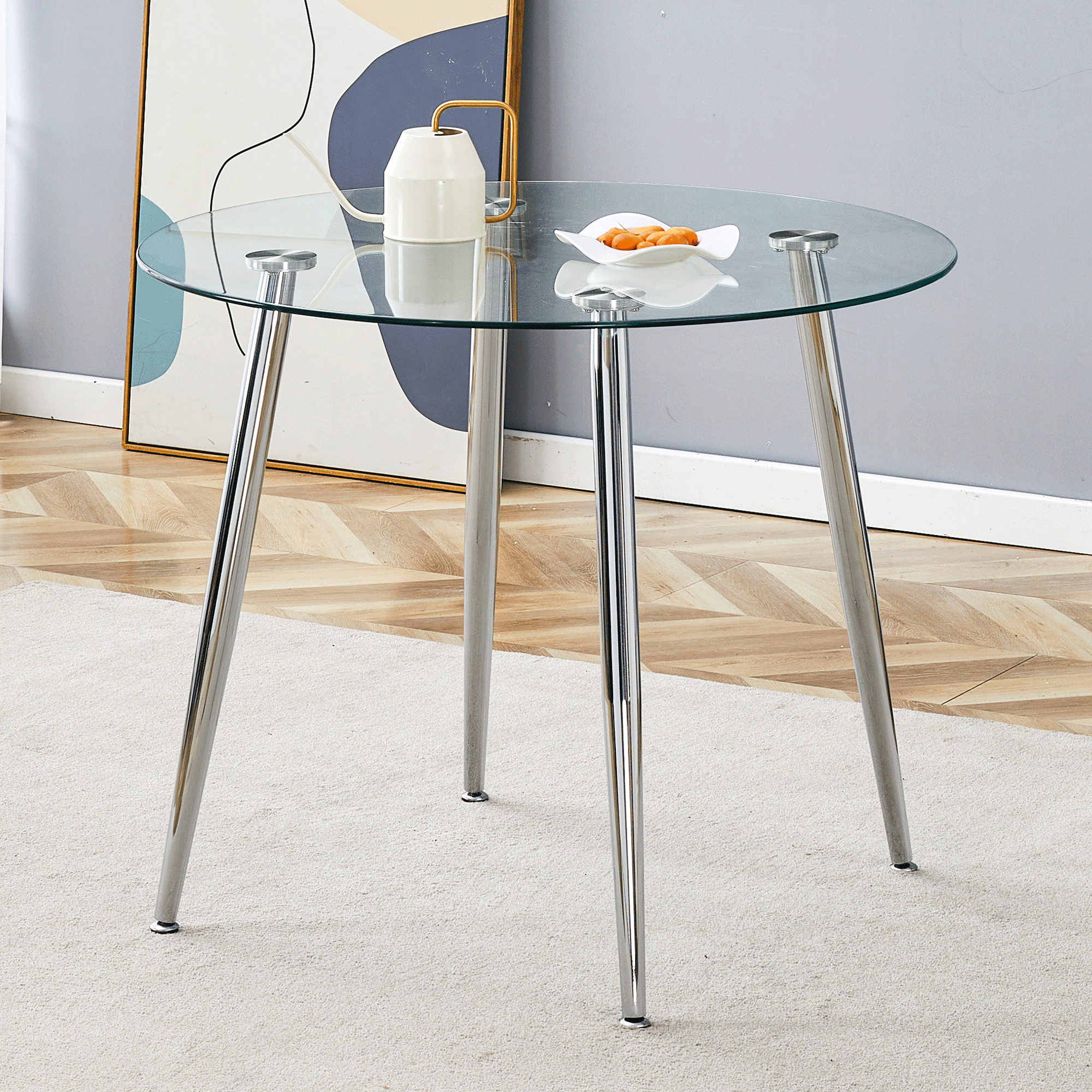 Front view of the round glass dining table styled with a watering can and fruit dish in a bright room