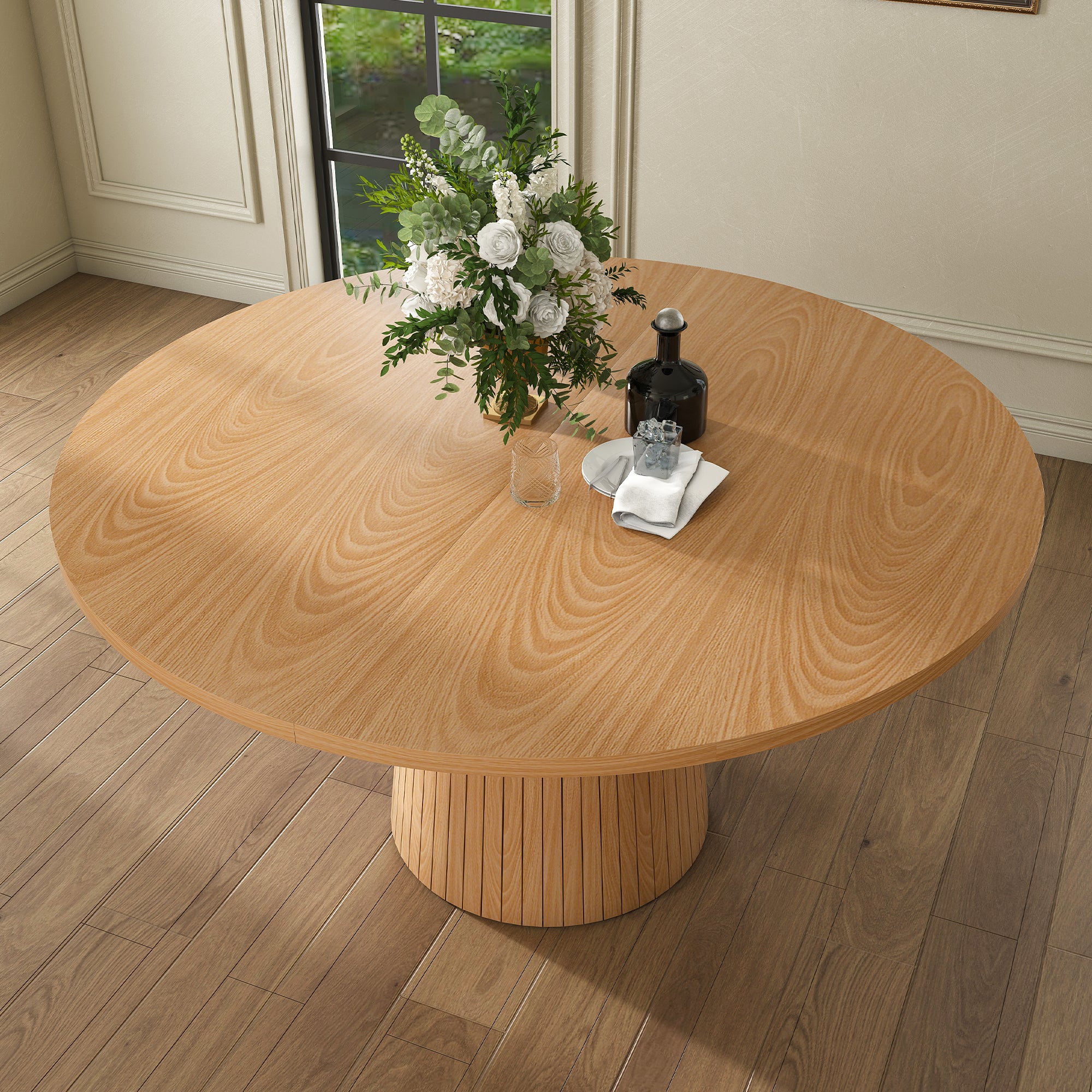 High angle of oak round dining table styled with white roses and a decanter near a window