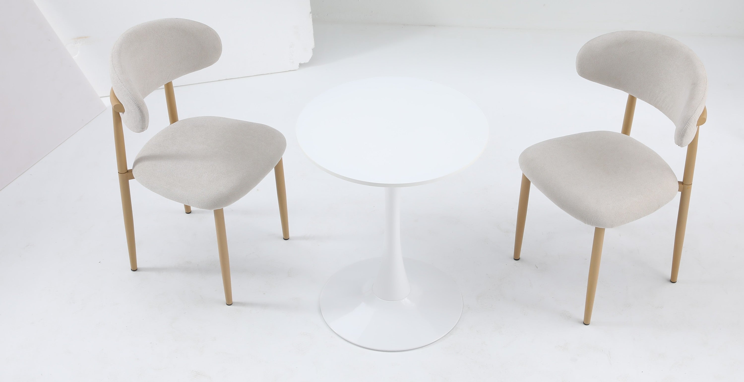 Overhead view of the white round bistro table paired with two beige chairs in a studio