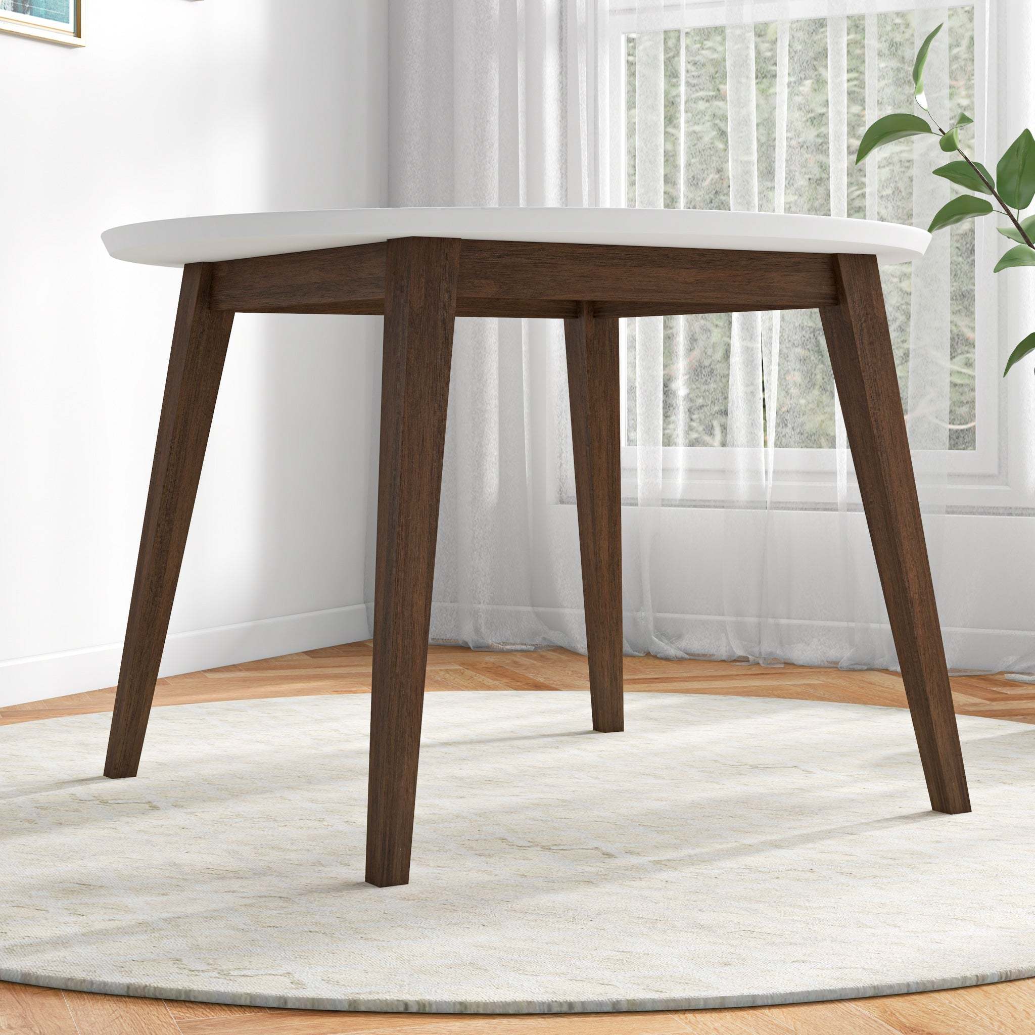 White round dining table styled near a window with sheer curtains
