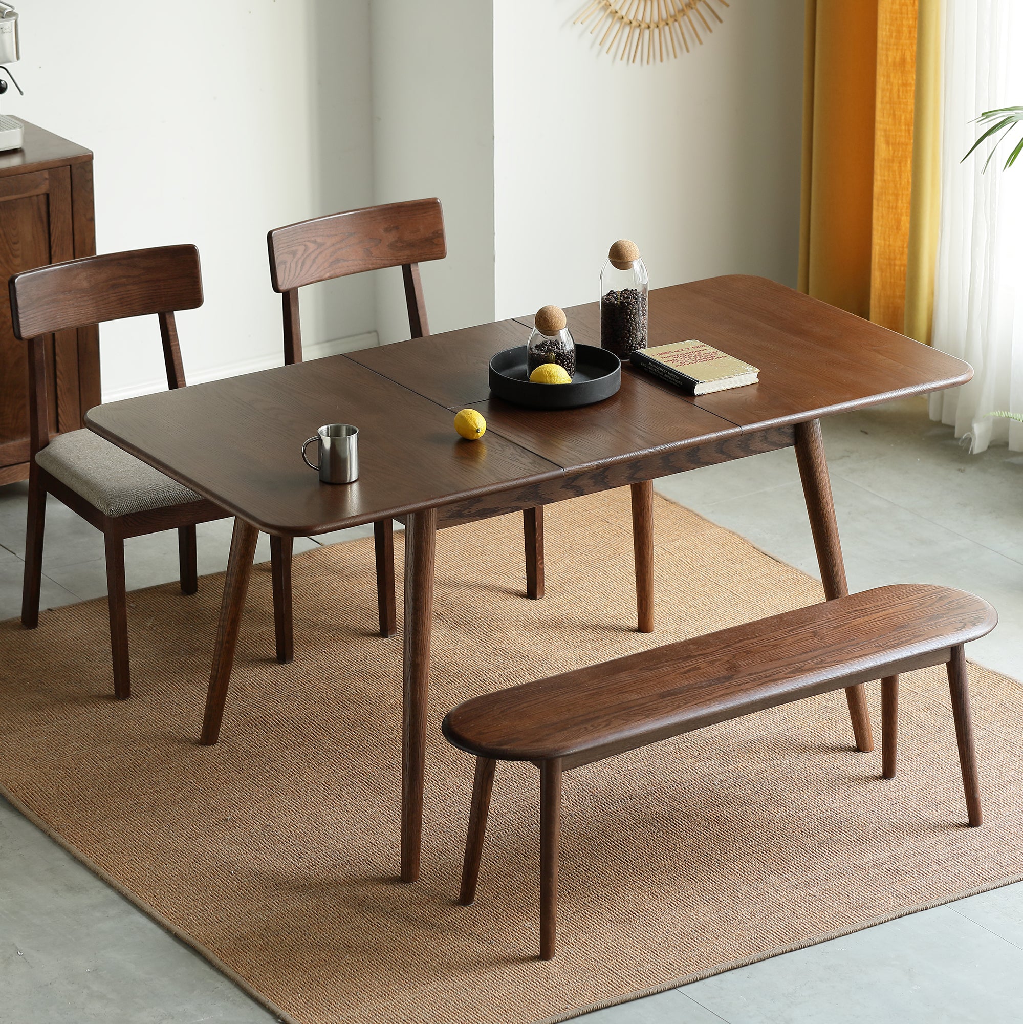 Walnut oak dining table with two chairs and a bench in a styled dining room