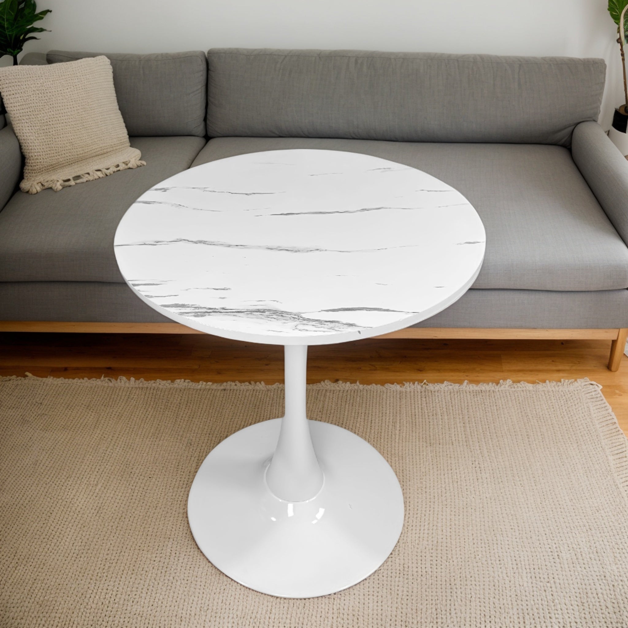Overhead view of the white marble tulip bistro table in front of a gray sofa