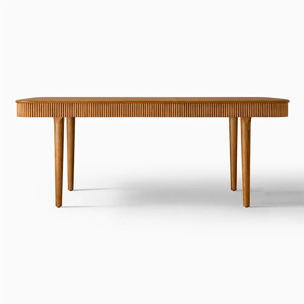 Full view of extendable ash wood dining table with fluted sides, warm brown finish, and modern mid-century silhouette.