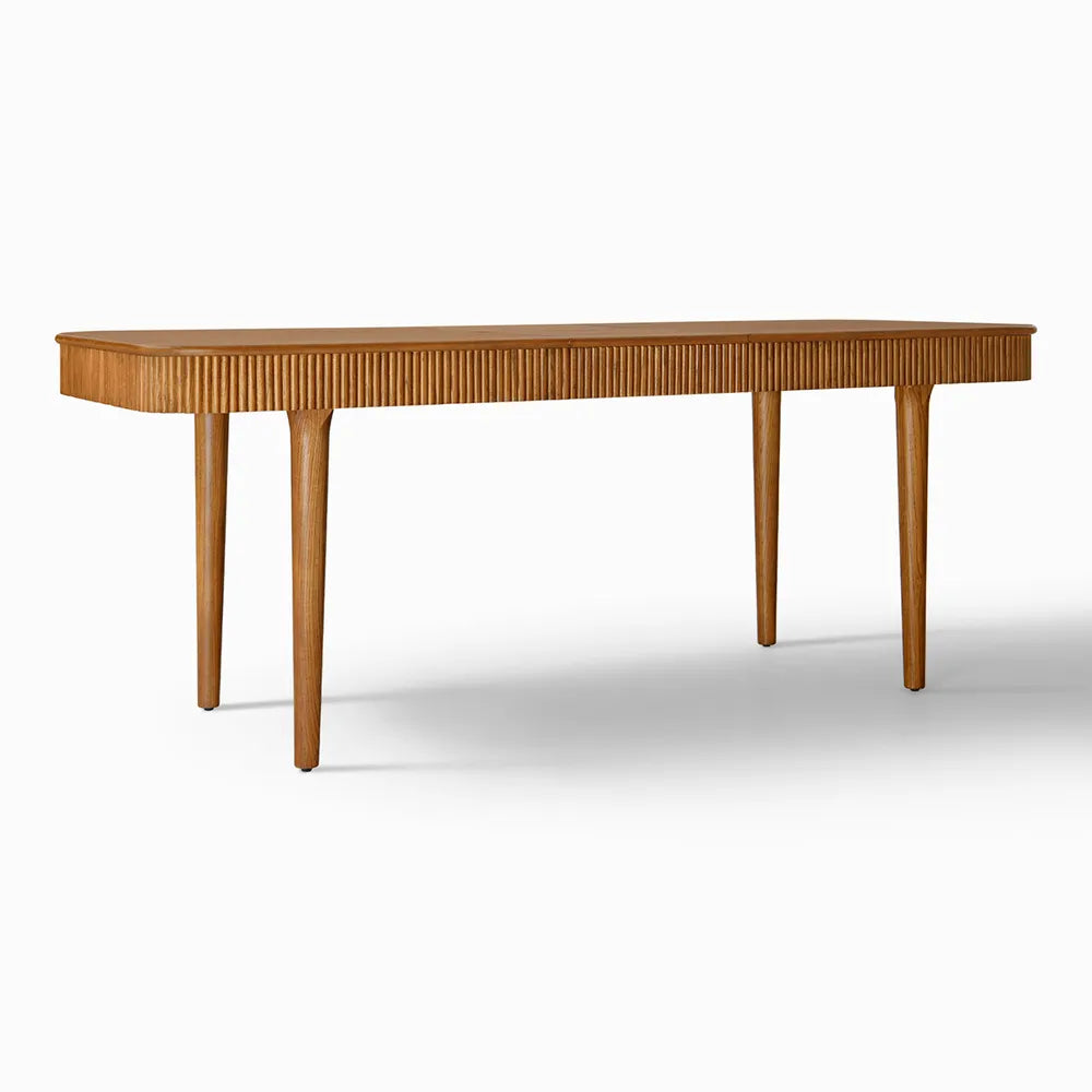 Angled view of modern extendable ash wood dining table featuring fluted detailing and rich brown finish, styled for a mid-century inspired dining area.