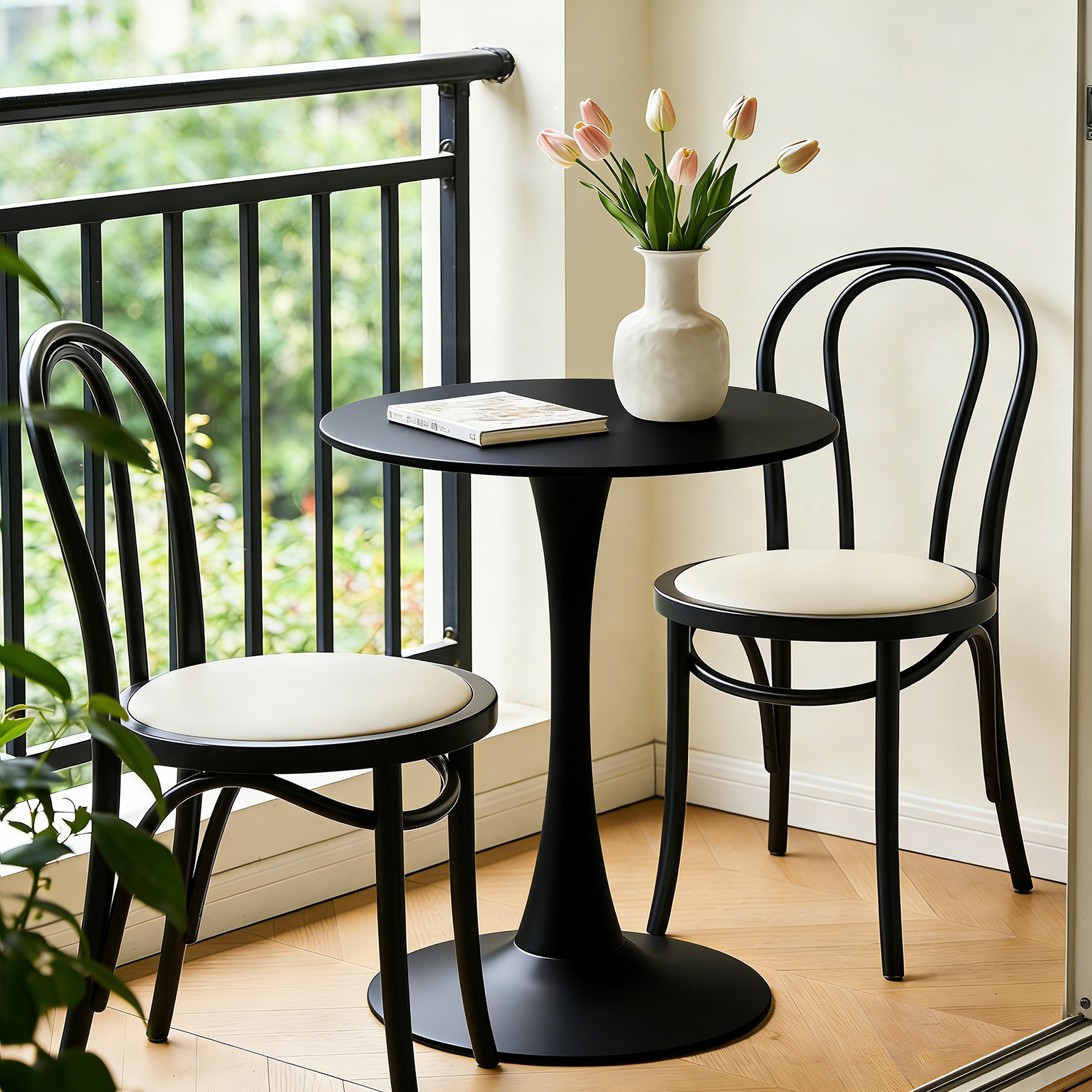Black round bistro table with two black bentwood chairs on a sunny balcony