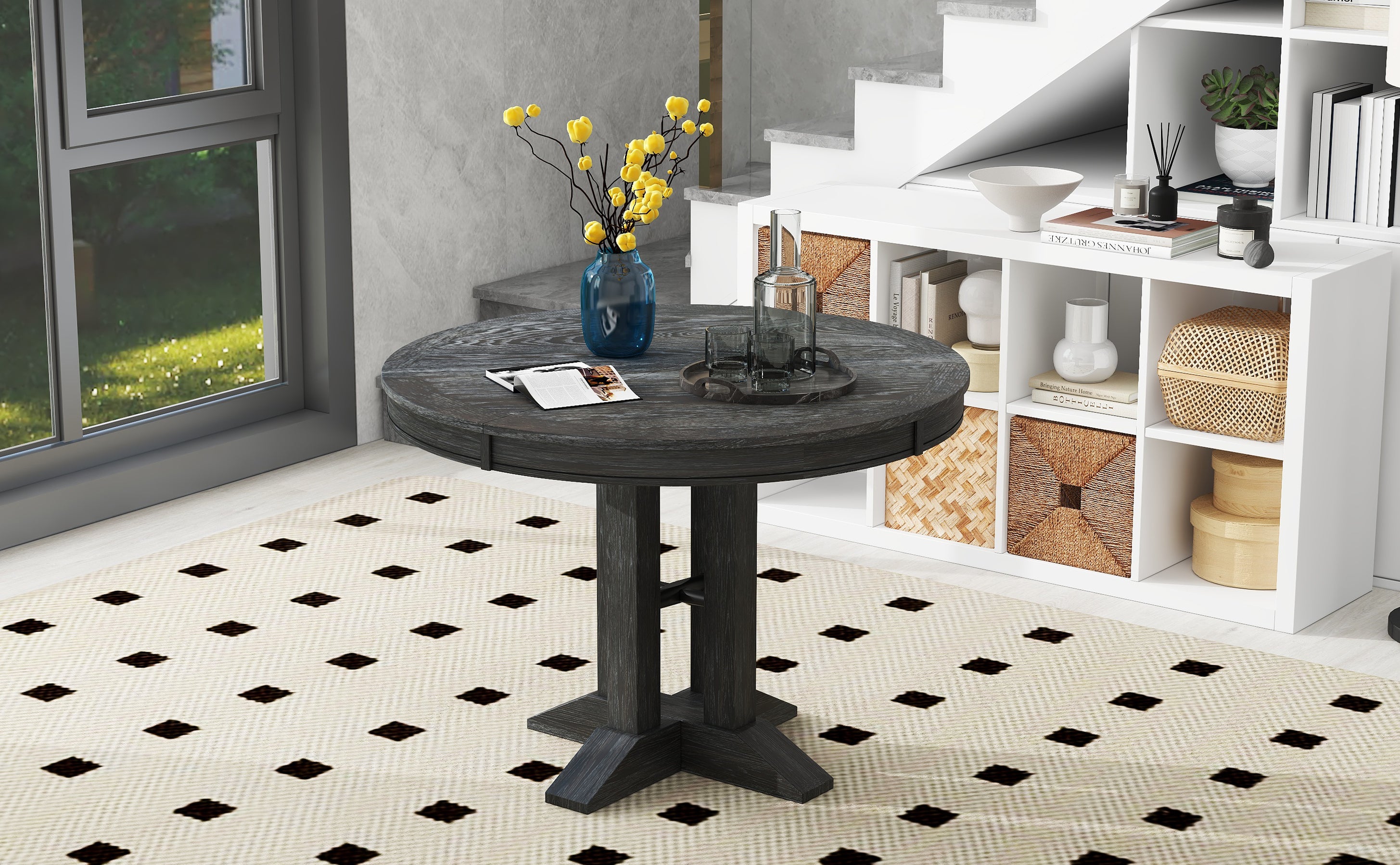 Black oval-extended dining table with vase and tray, styled by a window