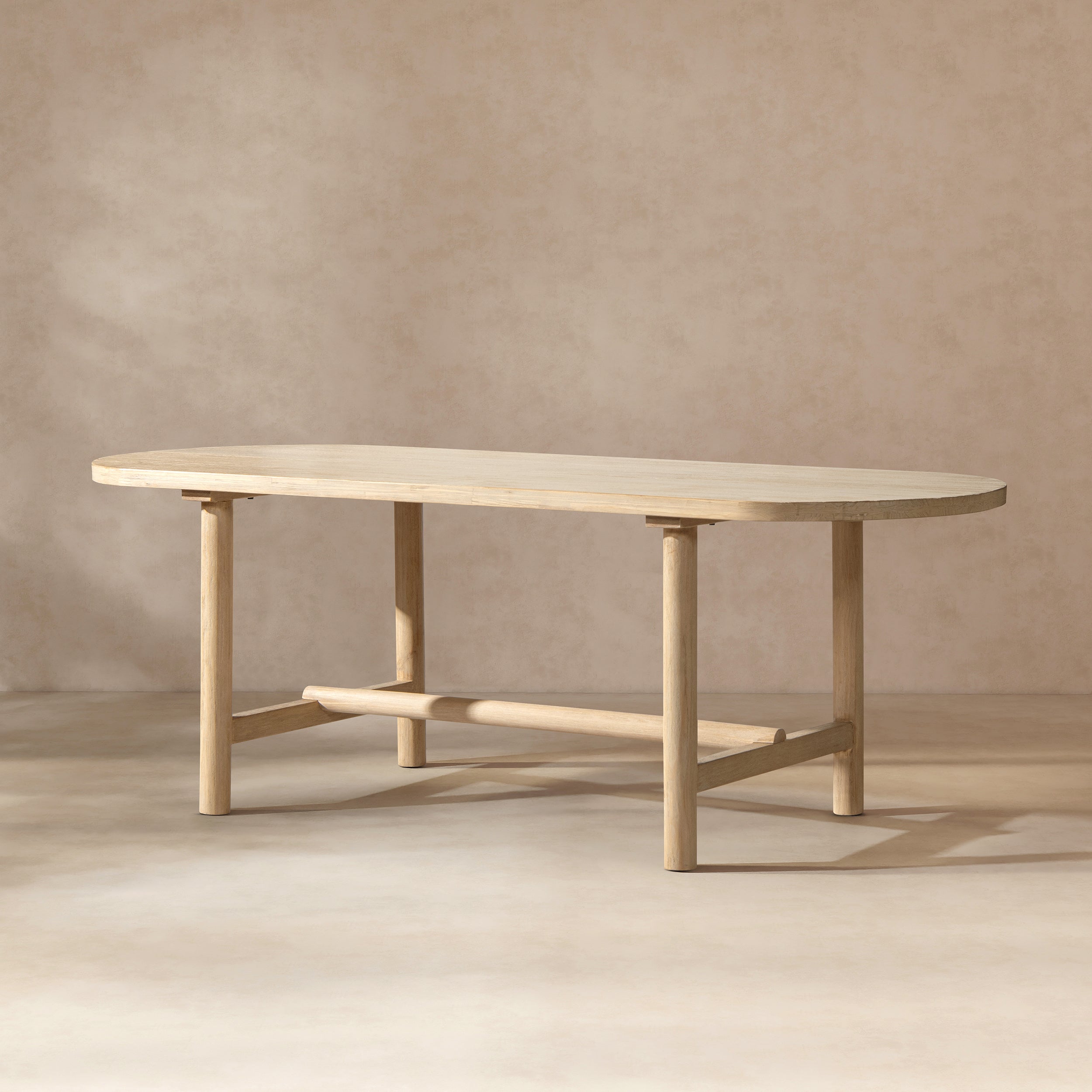 Natural cerused pine oval dining table, three-quarter view on beige studio background