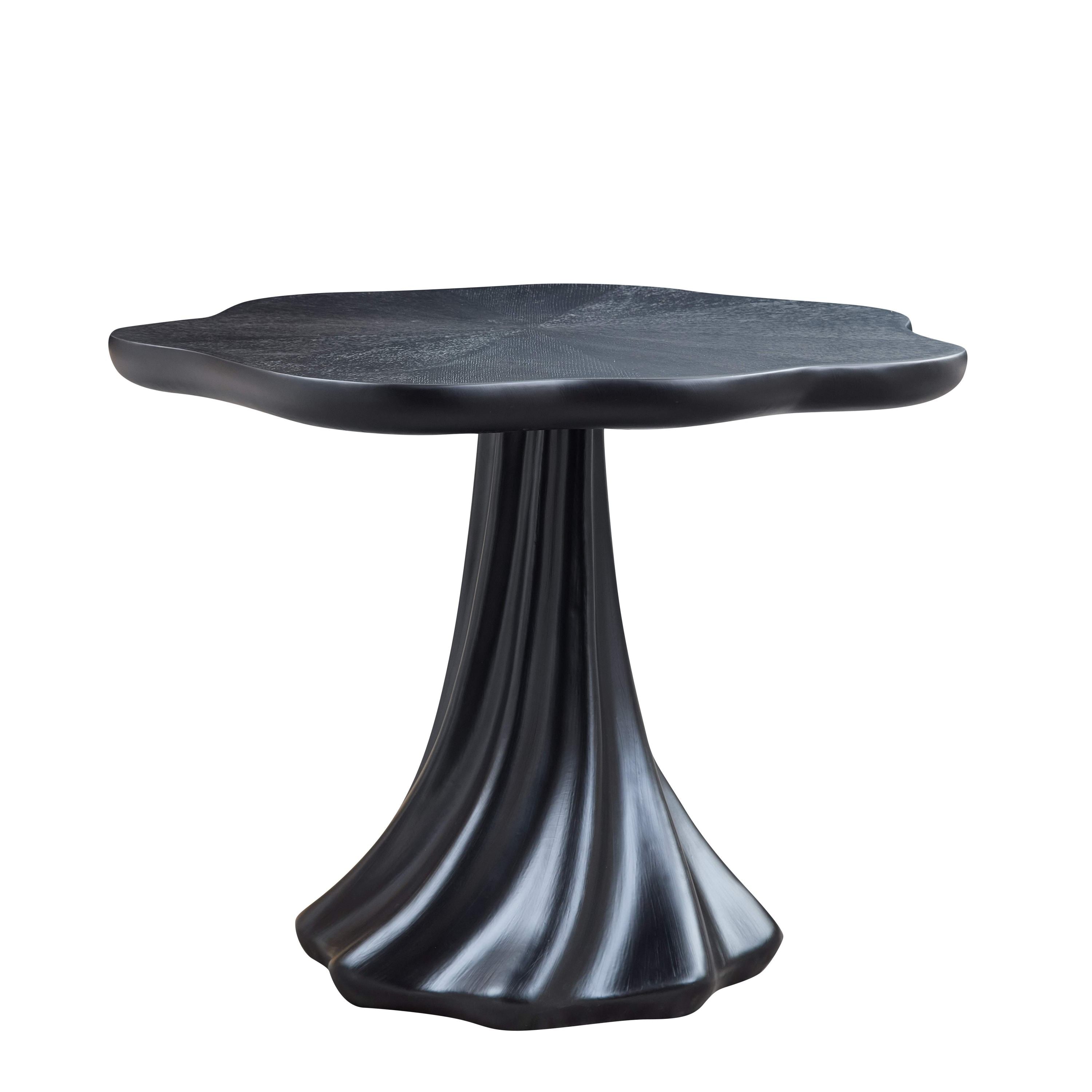 Black sculptural petal dining table with a fluted root-shaped pedestal on a plain white background, side view