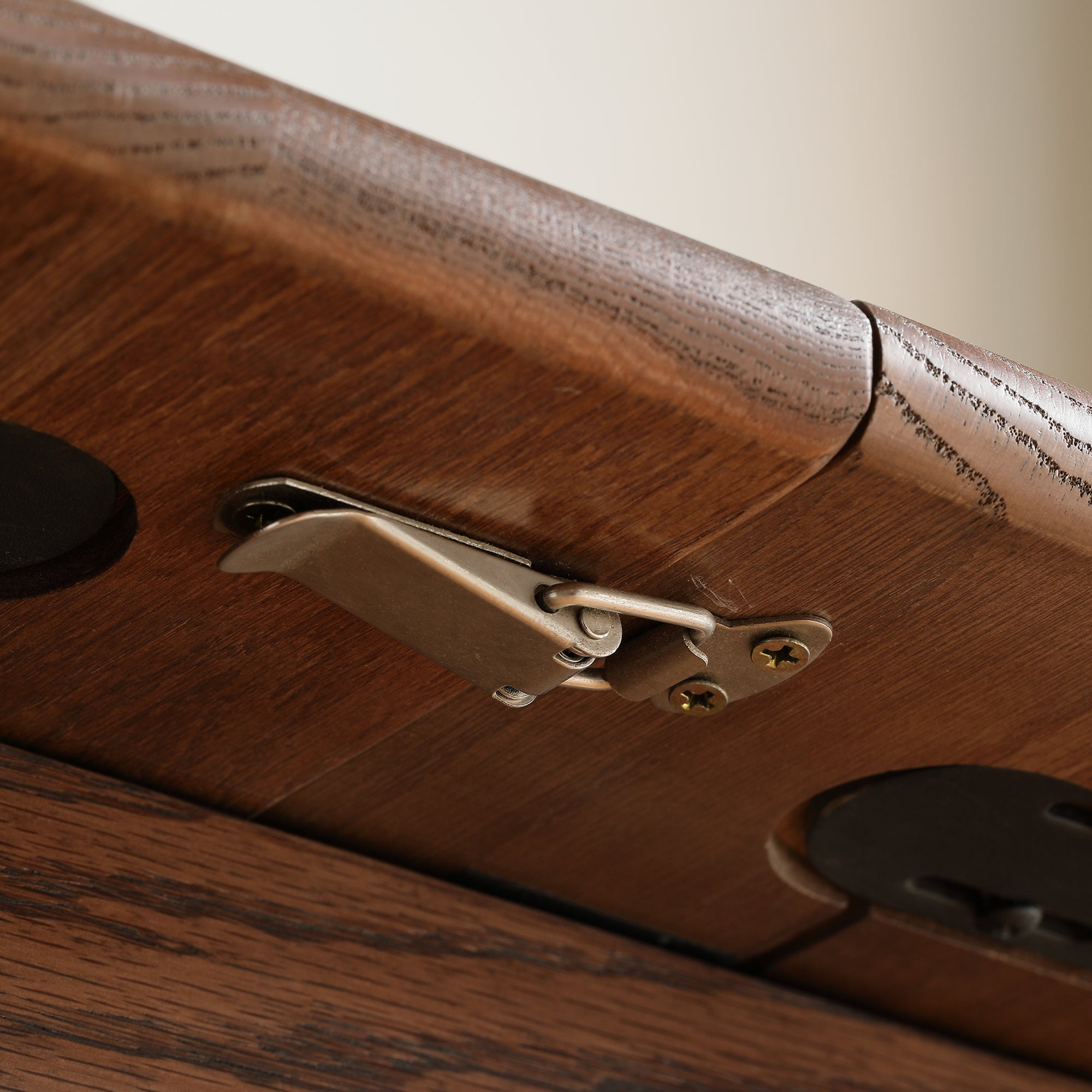 Close-up of a brass locking latch under the walnut oak tabletop