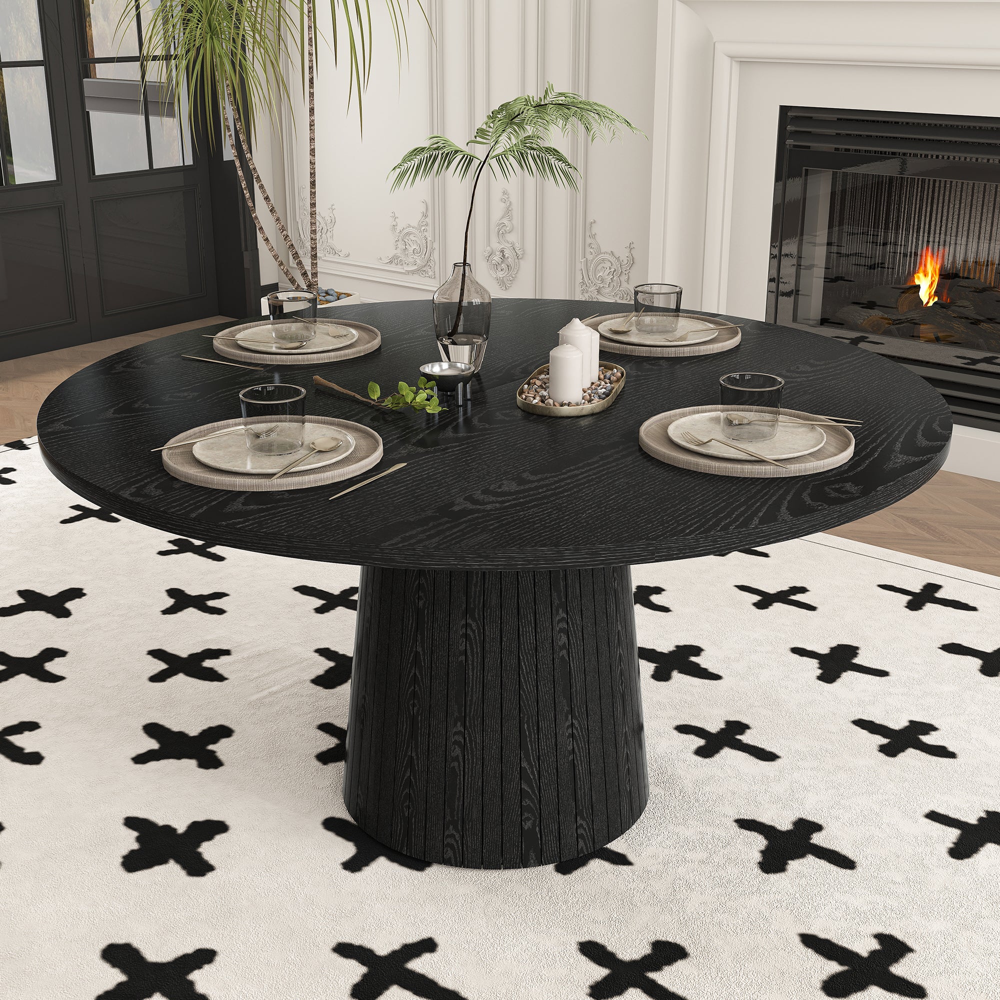 High angle of black round dining table set for four beside a fireplace on a cross-pattern rug