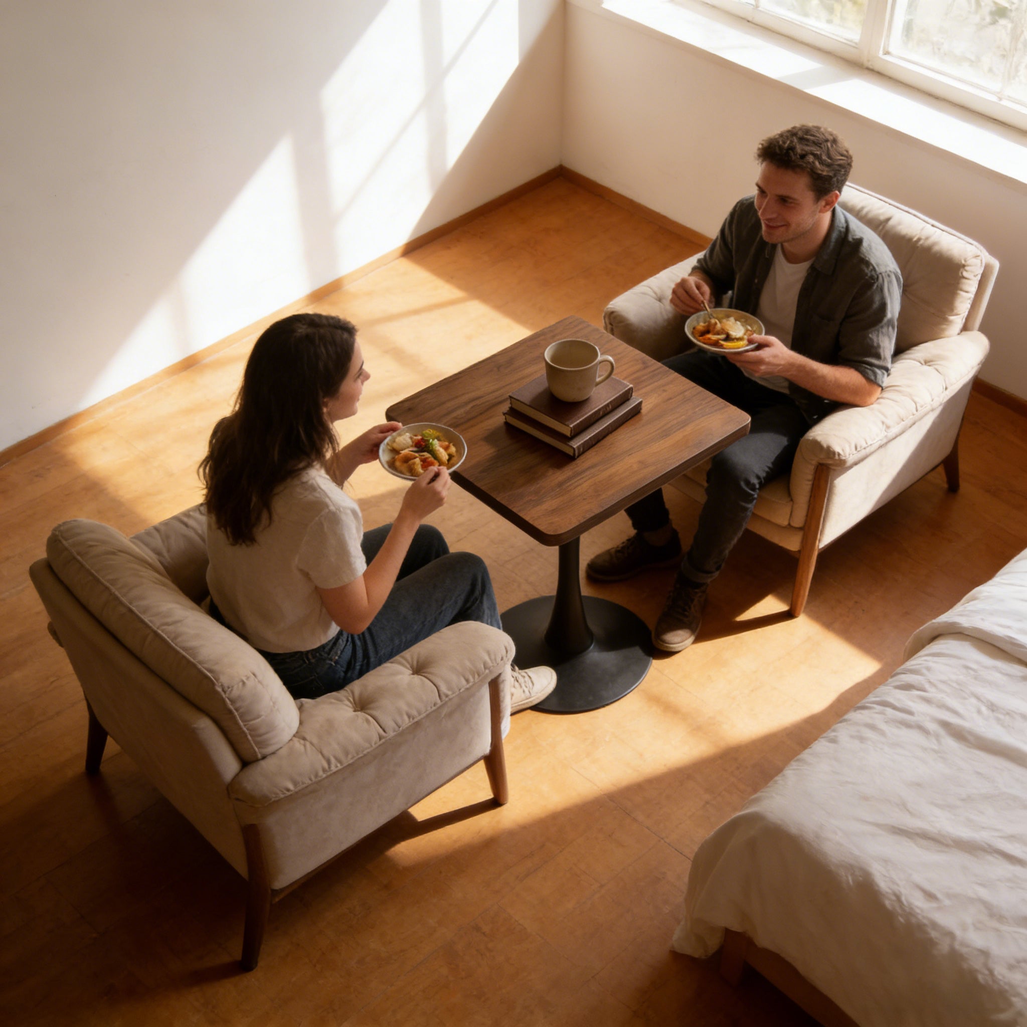 Overhead view of a couple eating on upholstered sofas around the walnut square tulip bistro table