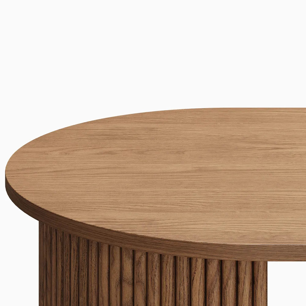 Detail of rounded wood tabletop with fluted leg base in a natural finish.