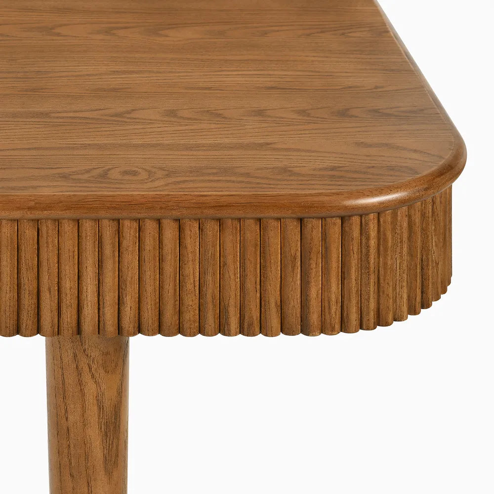 Close-up of ash wood dining table edge showing beveled detail and natural wood grain texture in warm brown finish.