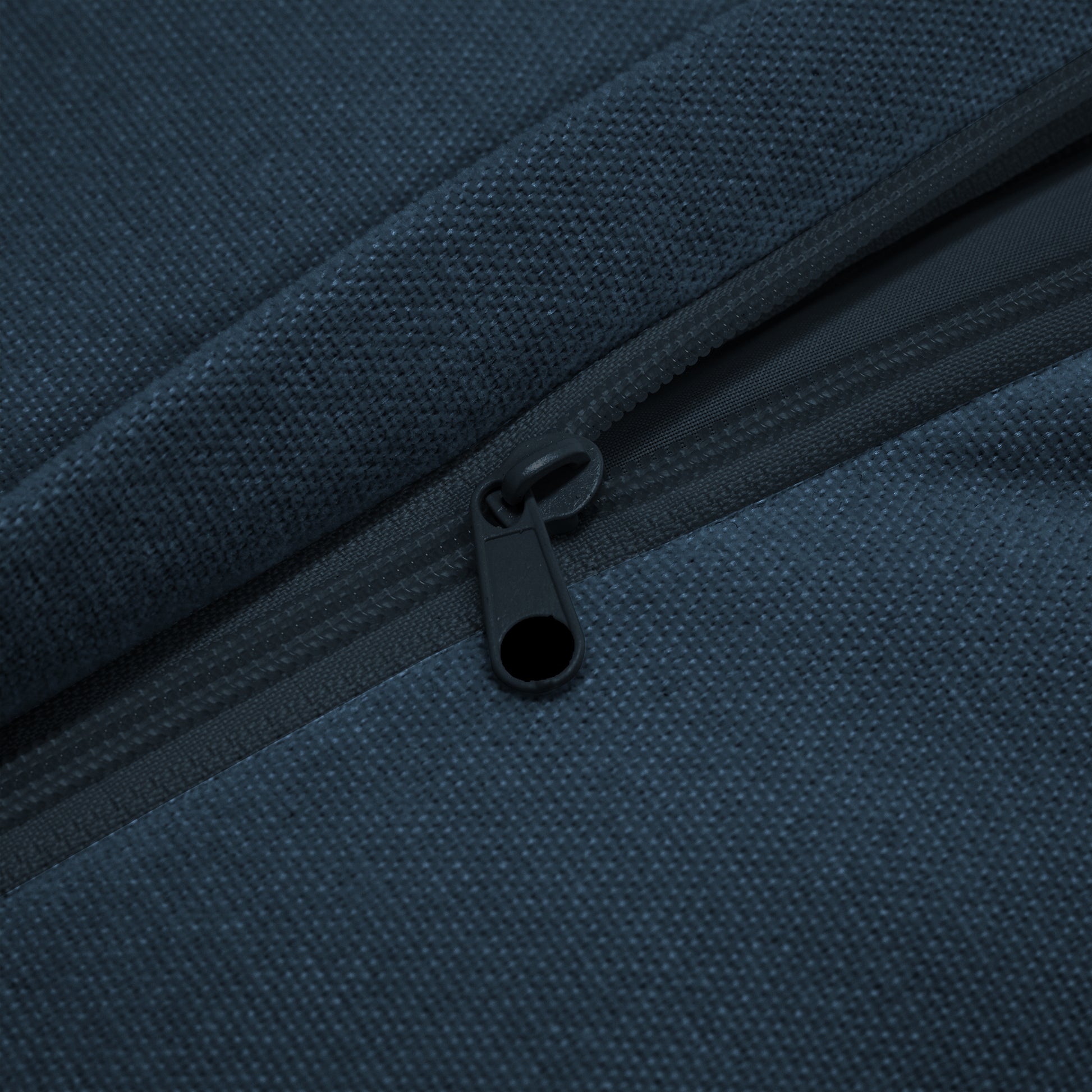 Close-up view of the navy chenille sectional showing the slipcover partially unzipped, emphasizing the machine washable design and easy-care functionality of the removable cover.