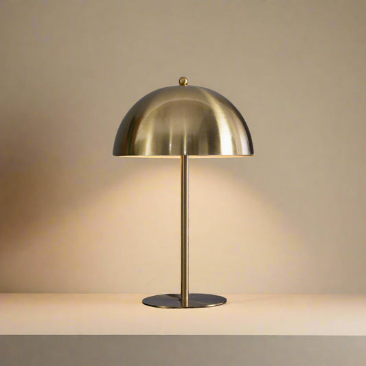 gold table lamp with dome shaped shade light is turned on and warm light is coming out
