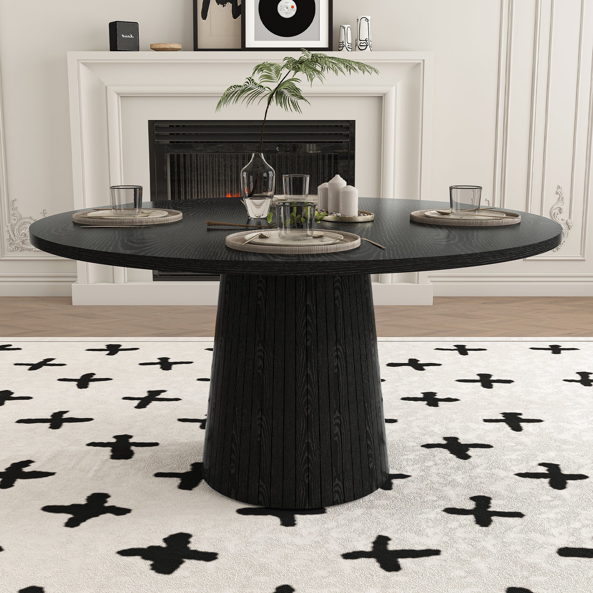 Black round dining table styled with tableware in front of a white fireplace with framed art