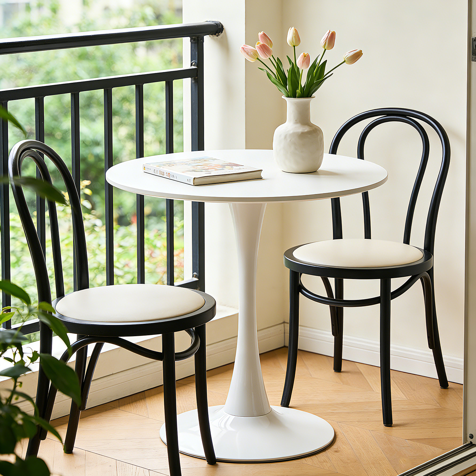 White round dining table with two black bentwood chairs and tulips on a sunny balcony
