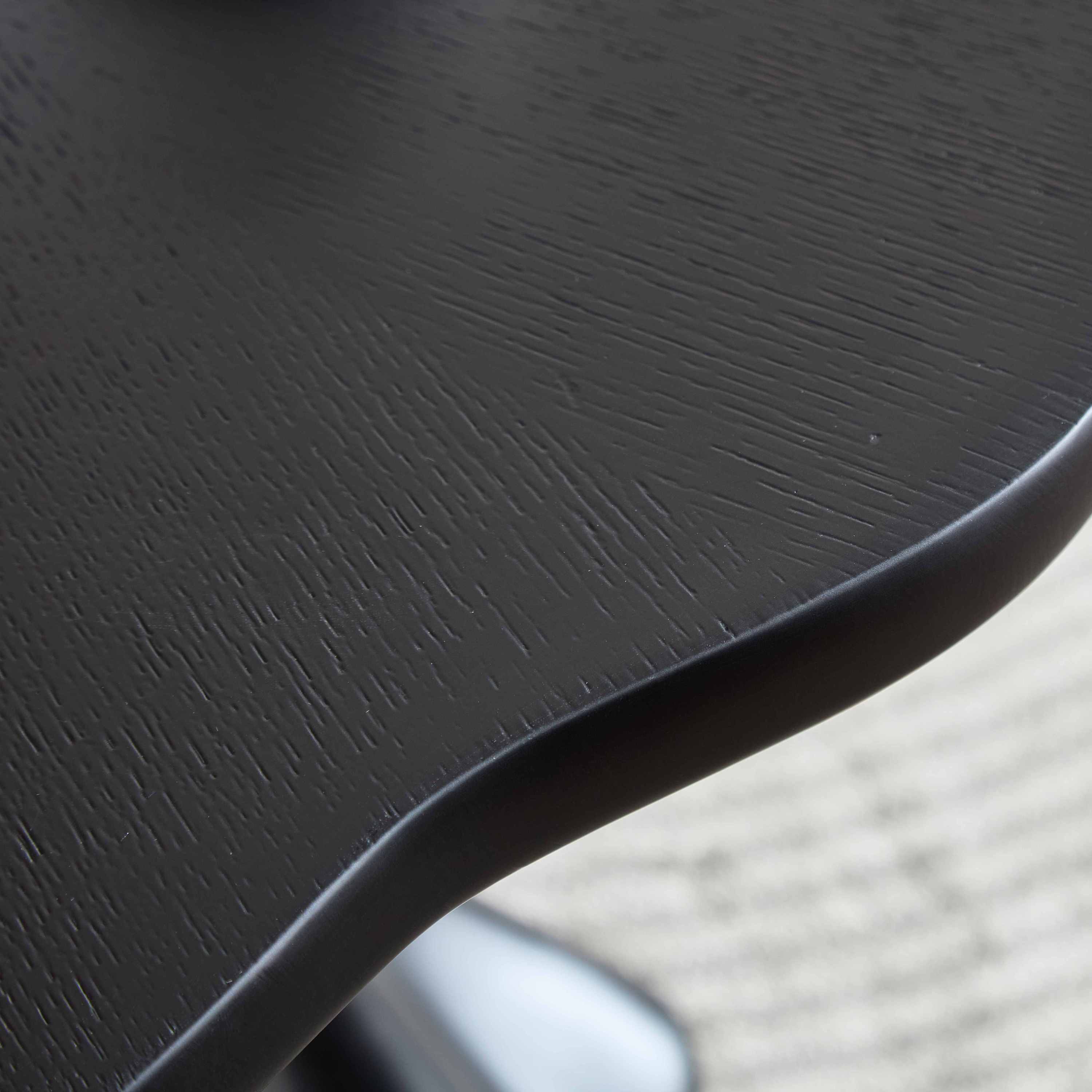 Close-up of the petal tabletop edge showing the black wood-grain finish